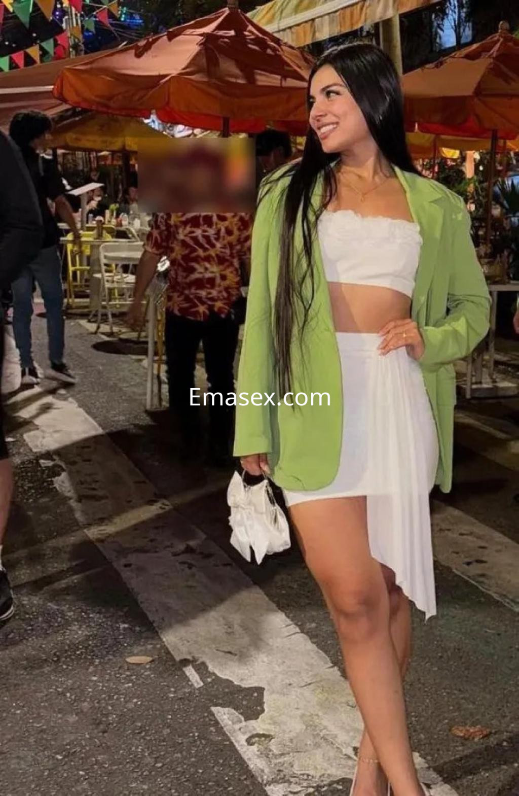 La puta viste un conjunto blanco con chaqueta verde en un ambiente festivo al aire libre en Zaragoza.