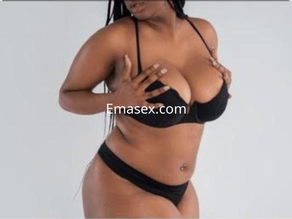 Escort en Pontevedra, posando de lado con lencería negra, cabello largo y trenzado, mostrando confianza.