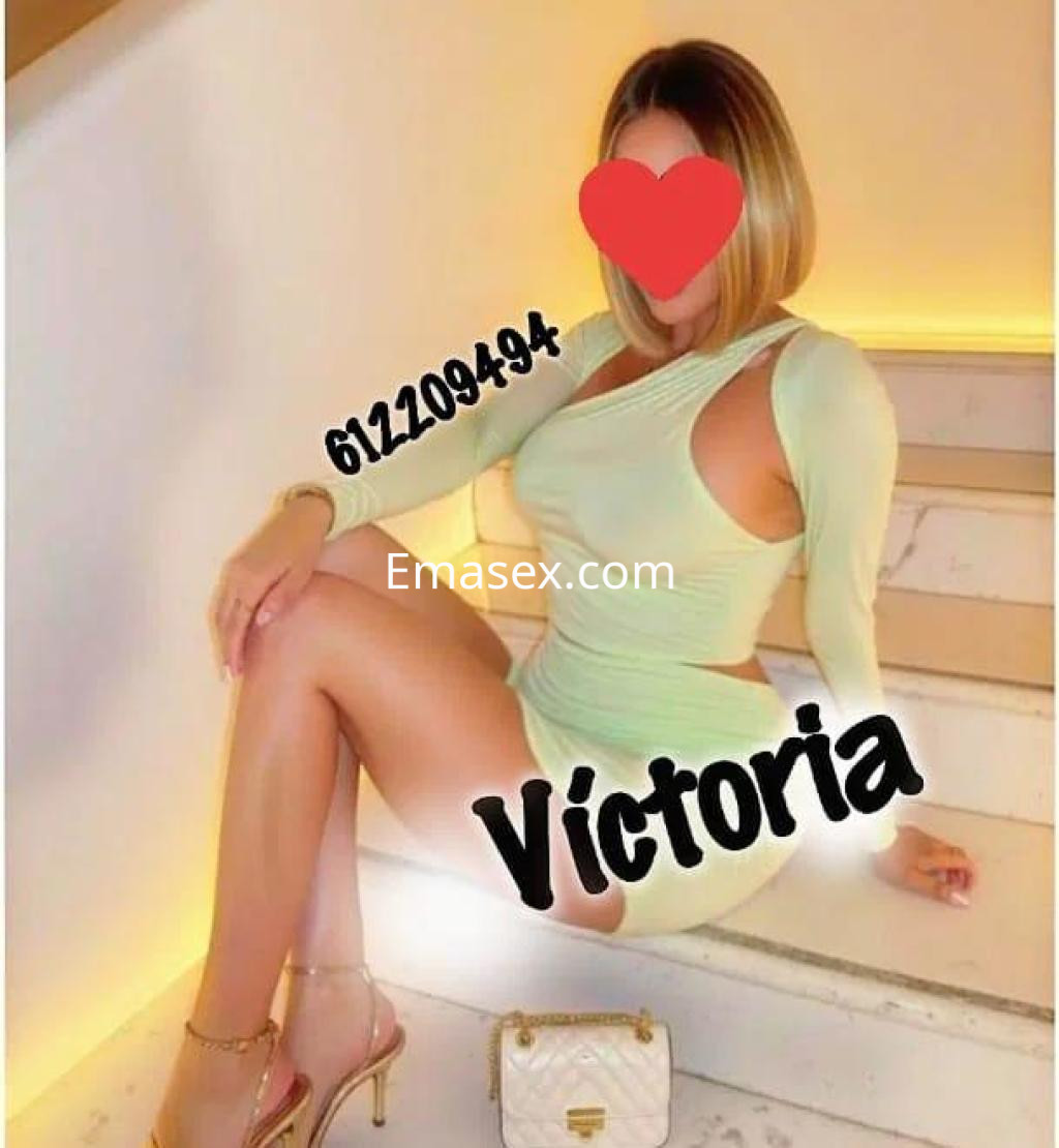 Puta en Alicante vestida con un conjunto verde claro, posando sentada en escaleras con cabello rubio.