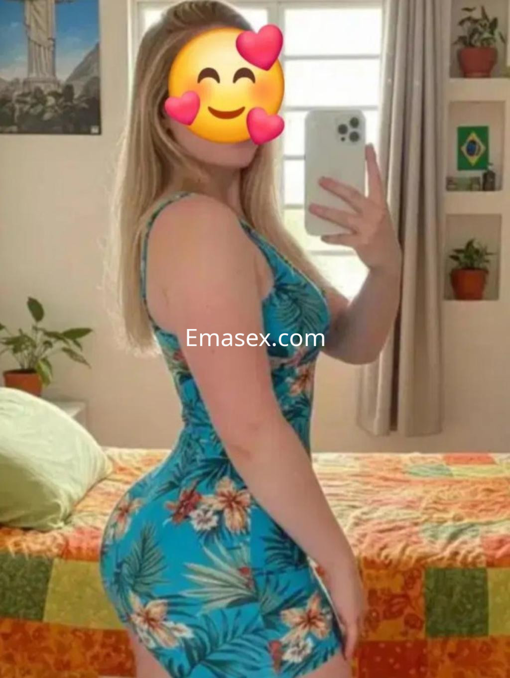 Puta posando de perfil en León, vistiendo un ajustado vestido de flores en tonos azules y verdes.