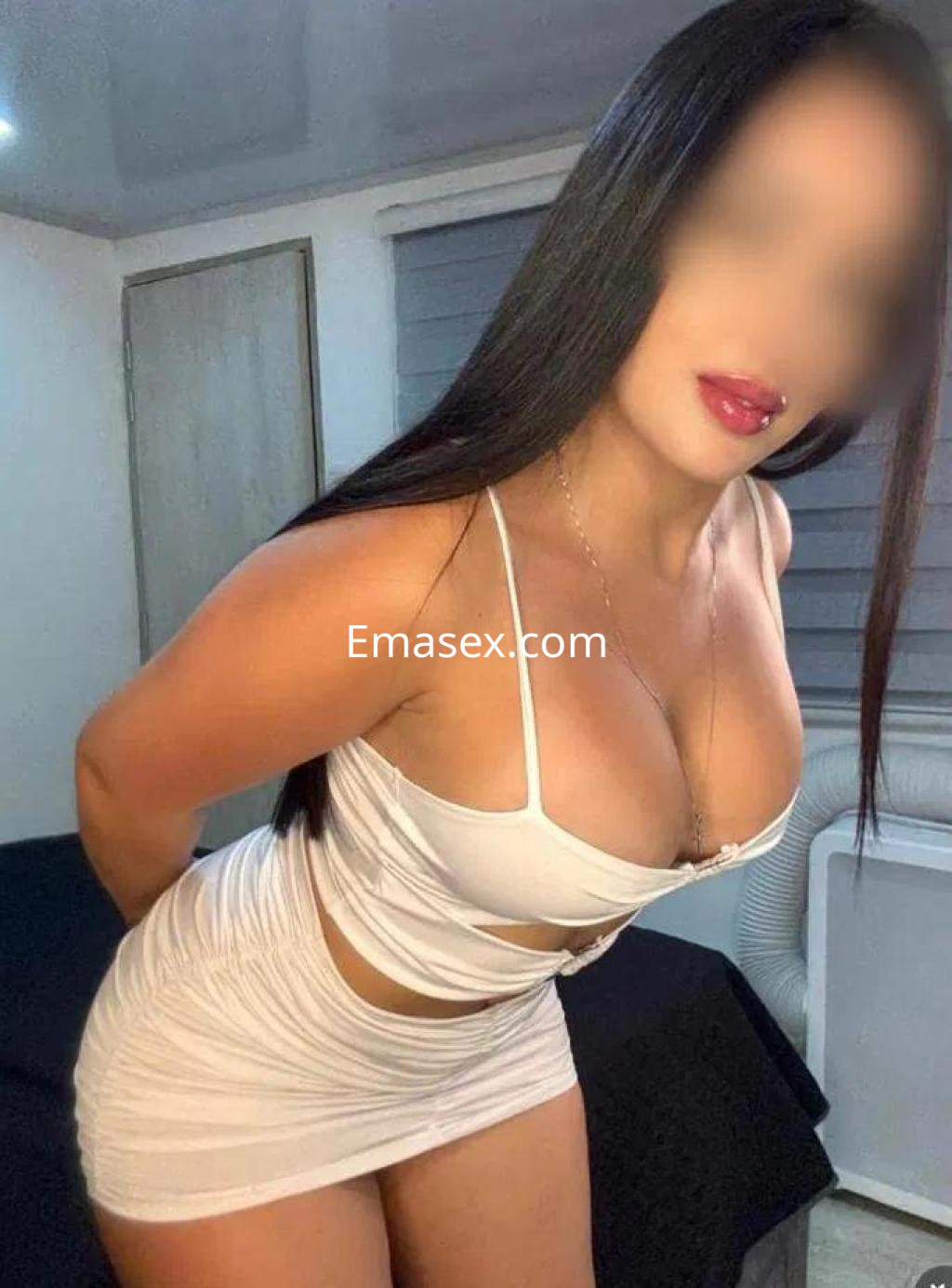 Escort en Murcia con cabello largo y oscuro, vistiendo un vestido blanco ajustado que resalta su figura.