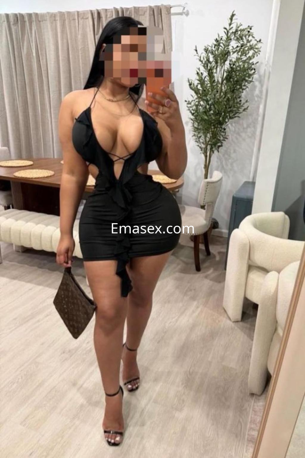 Escort en Pontevedra vistiendo un vestido negro ajustado con escote pronunciado, sosteniendo una bebida en la mano.