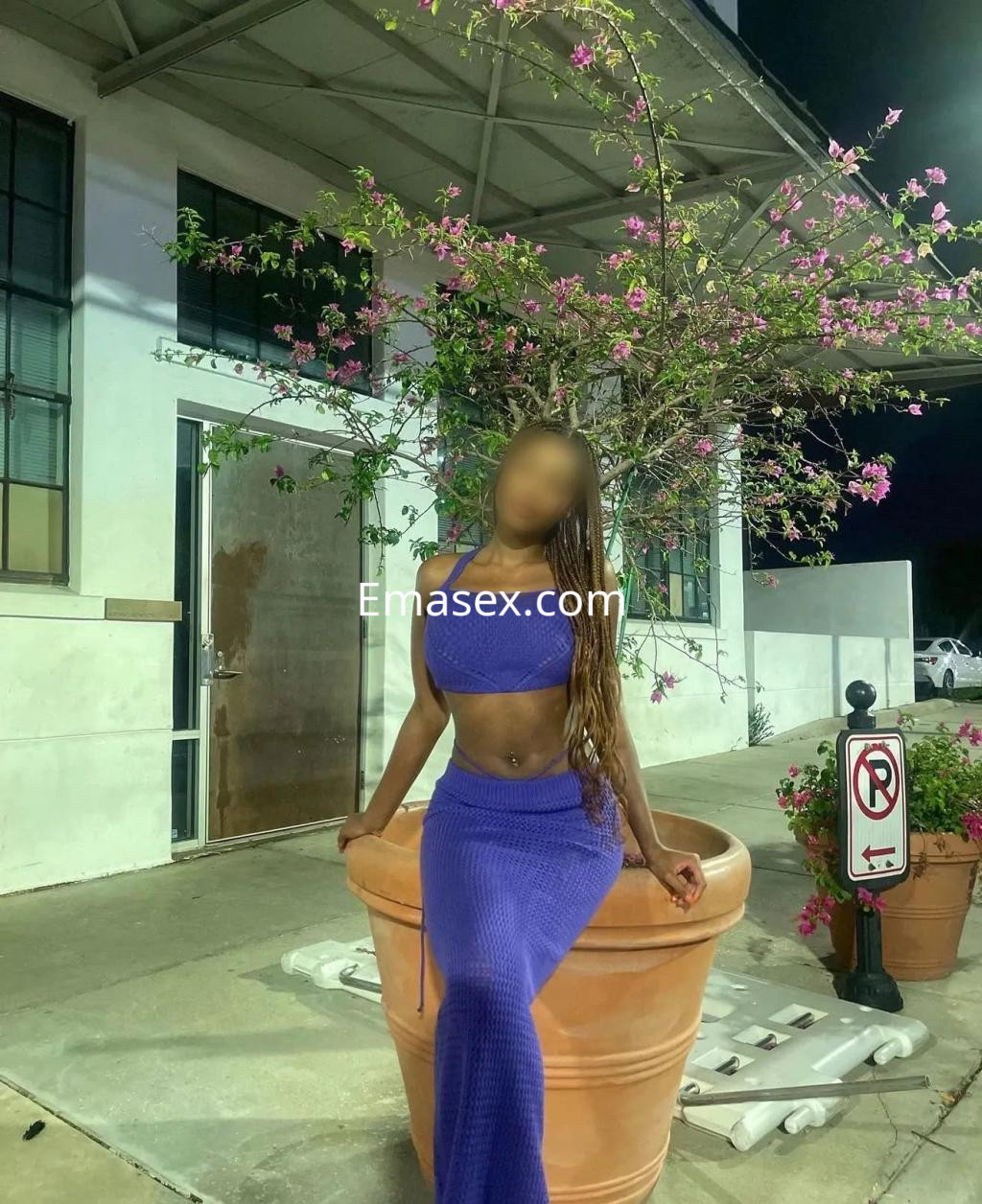 Escort en Vigo con cabello largo y lacio, vistiendo un top azul y una falda larga, posando junto a una planta.