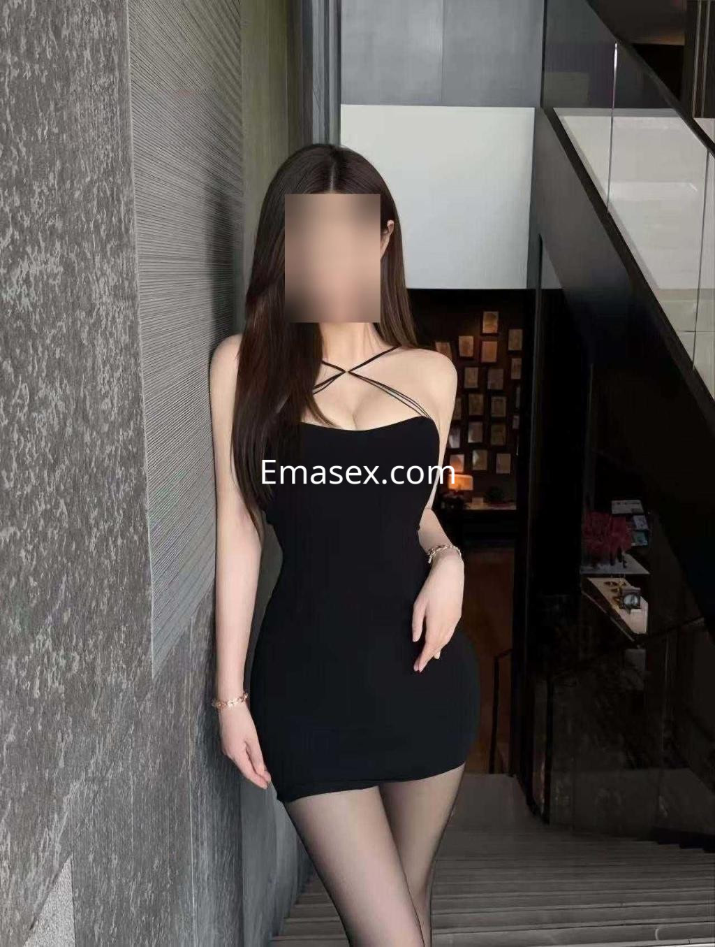 Puta posando en una escalera con un vestido negro ajustado y medias transparentes en Zaragoza.