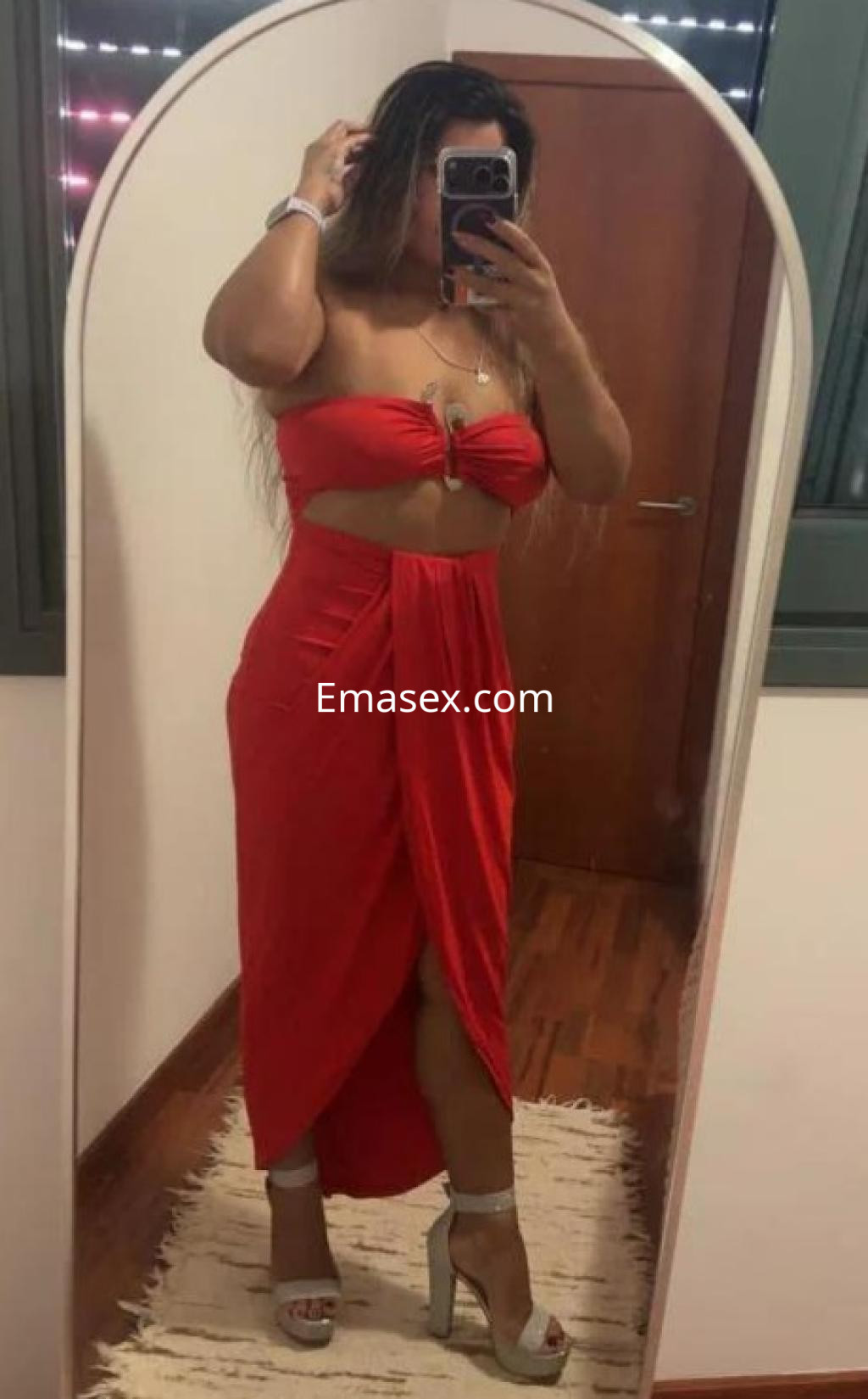 La puta en Barcelona luce un vestido rojo ajustado que realza su figura, con sandalias de tacón y cabello largo.