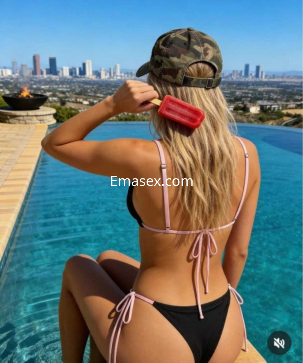 Escort en Albacete con cabello rubio y lacio, usando un bikini negro, disfrutando junto a una piscina.