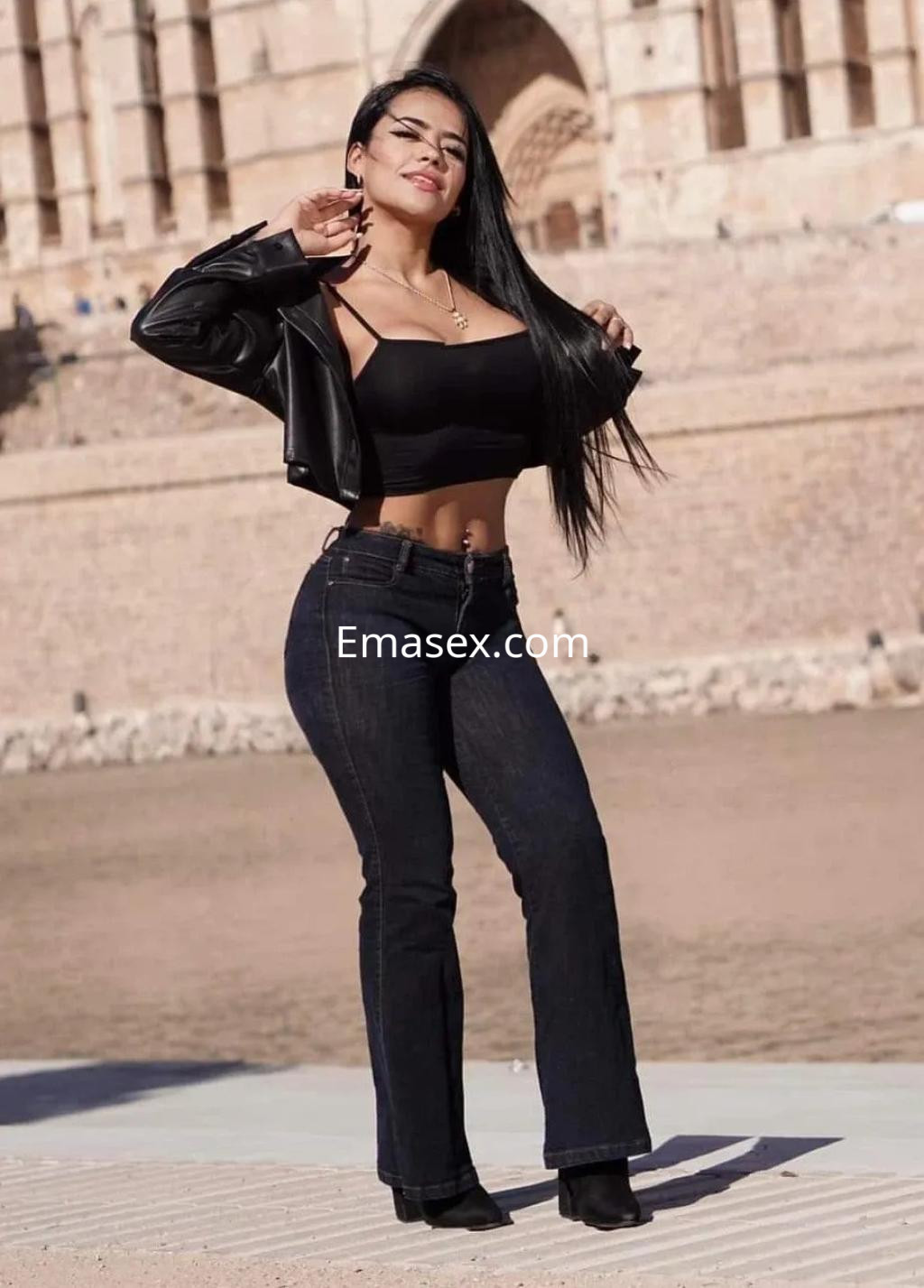 Escort en Palma de Mallorca, posando con una chaqueta de cuero negro y top ajustado, luciendo jeans de talle alto.