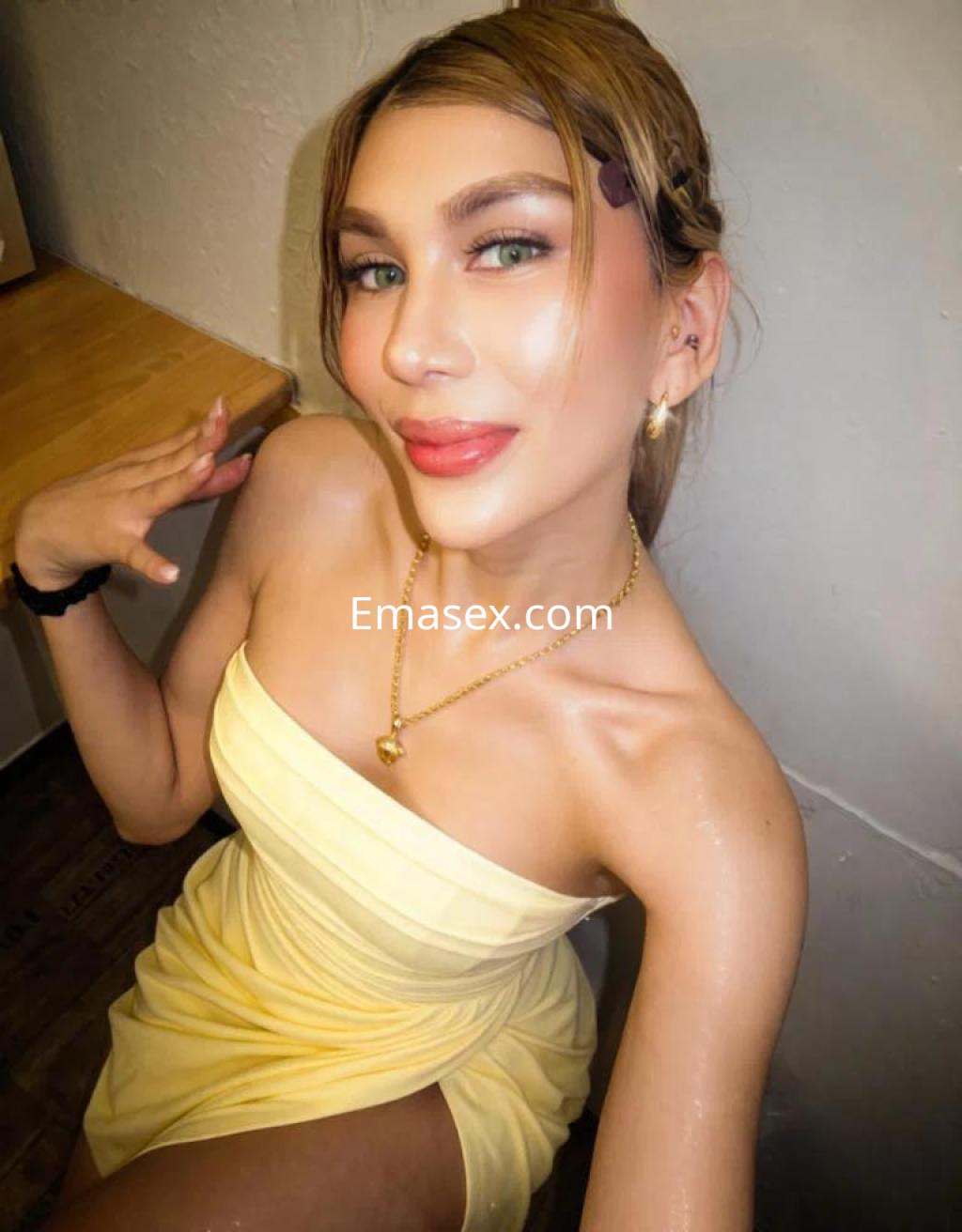 Escort en Barcelona con cabello largo y lacio, luciendo un vestido amarillo, posando sonriente en un entorno sencillo.