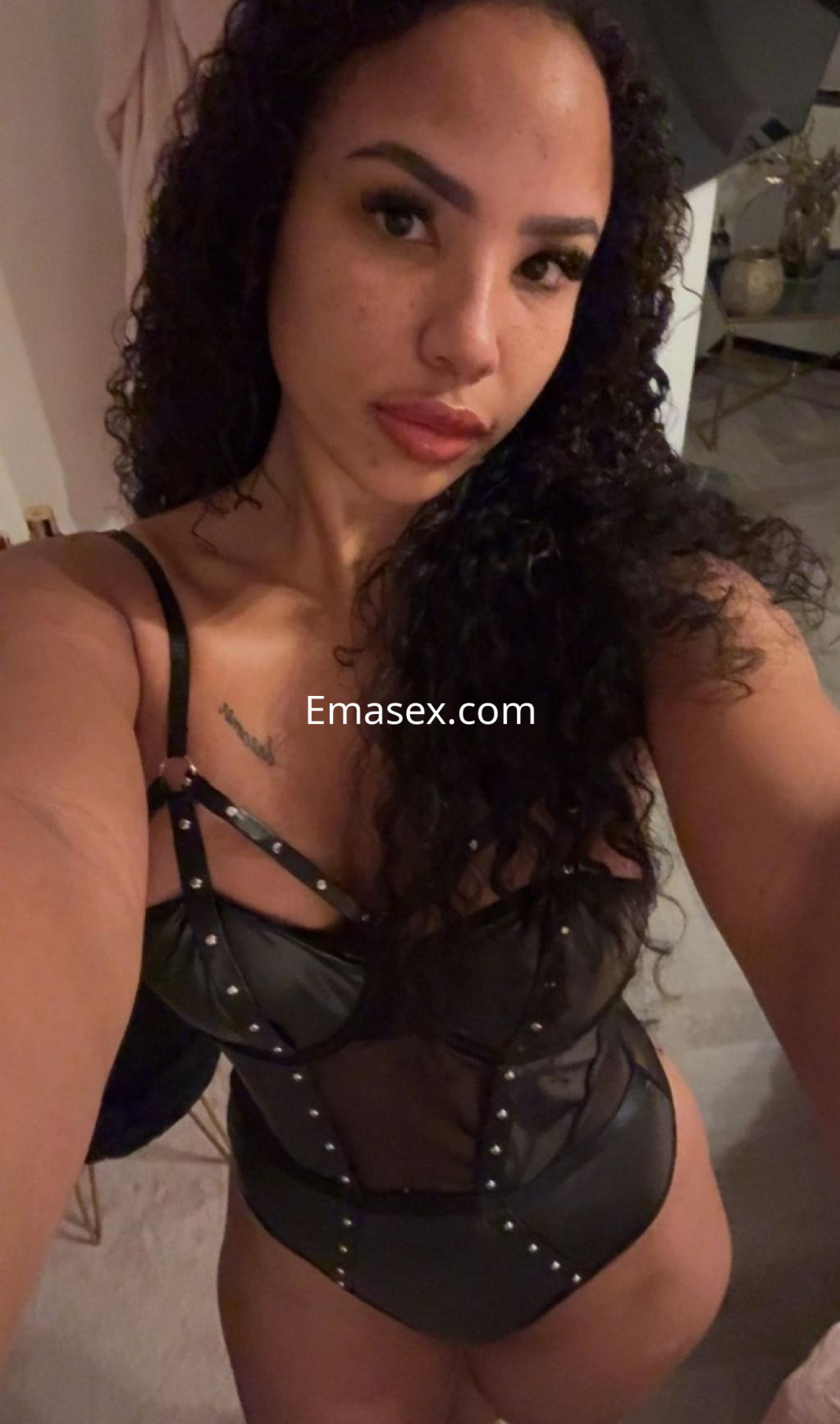 Puta con cabello rizado y oscuro, viste un body negro transparente con detalles metálicos en Salamanca.
