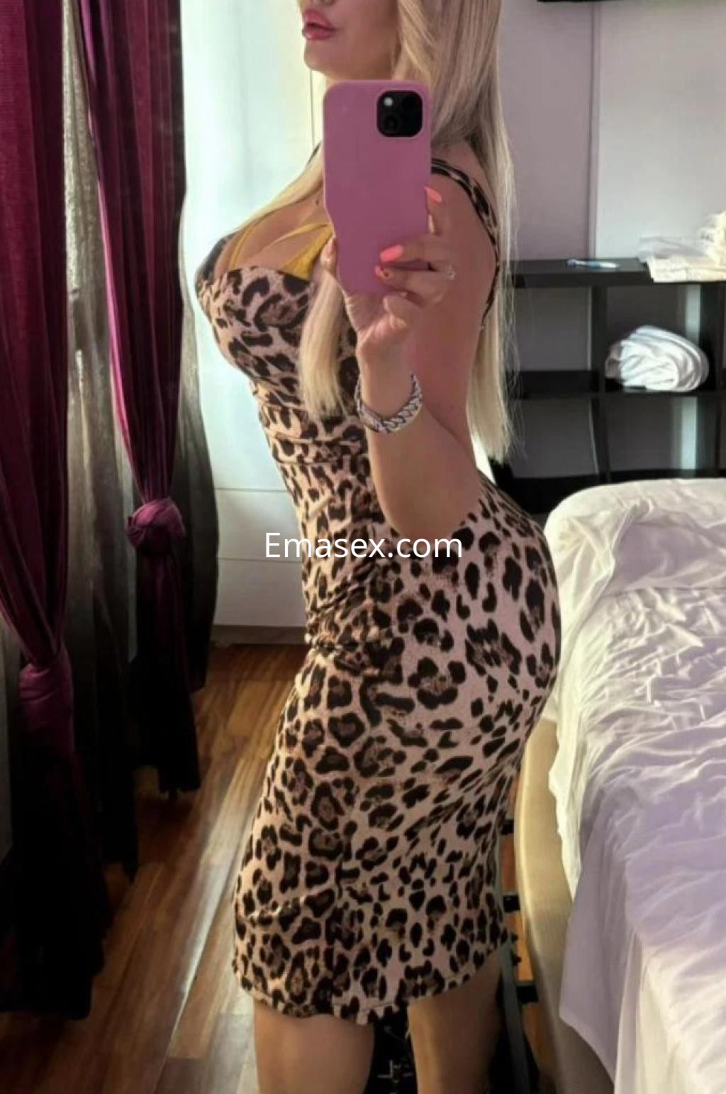Escort en Santander luciendo un vestido ajustado de estampado de leopardo, con cabello rubio y pose de perfil.
