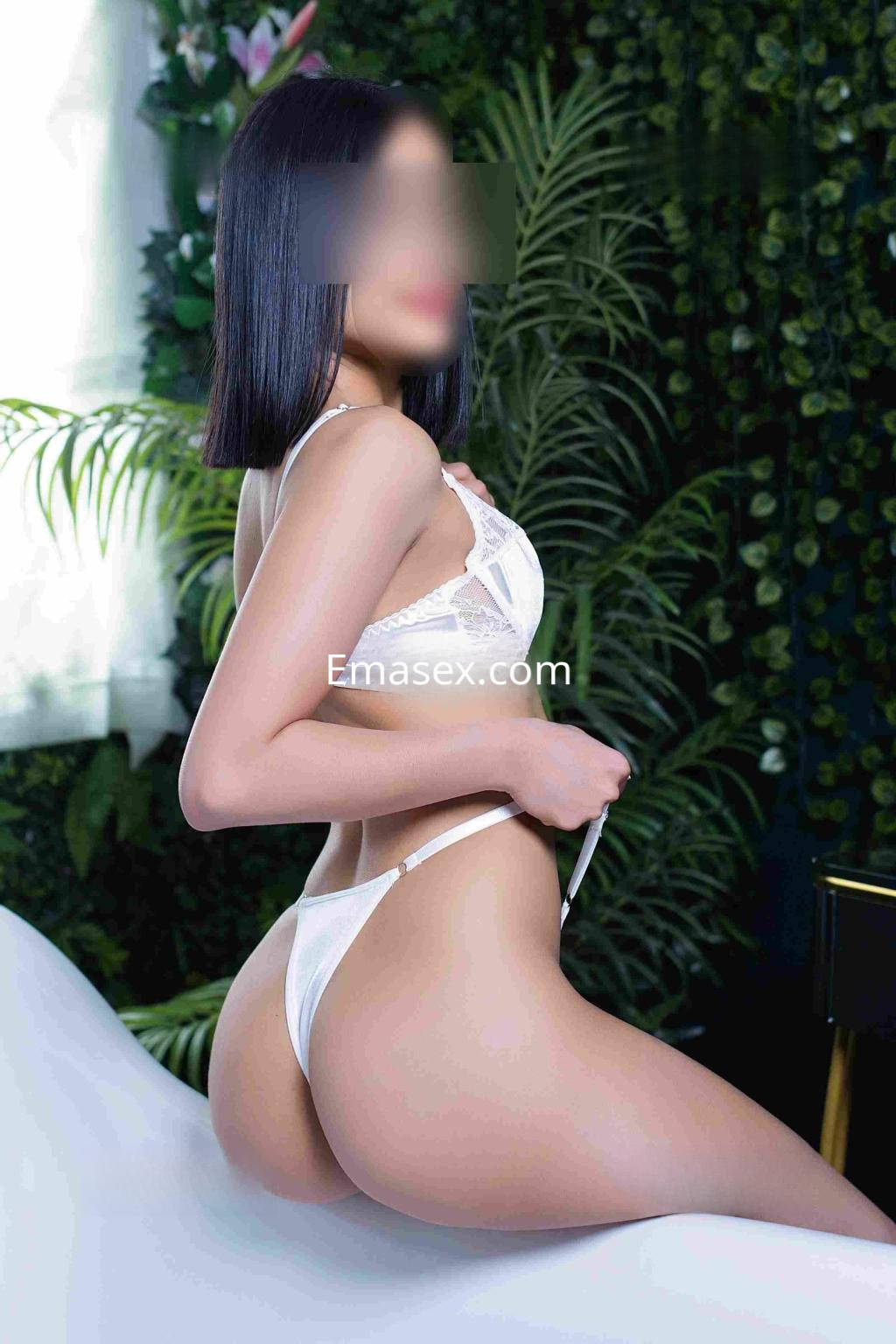 Escort en Barcelona con cabello corto y lacio, viste lencería blanca en un ambiente elegante y natural.