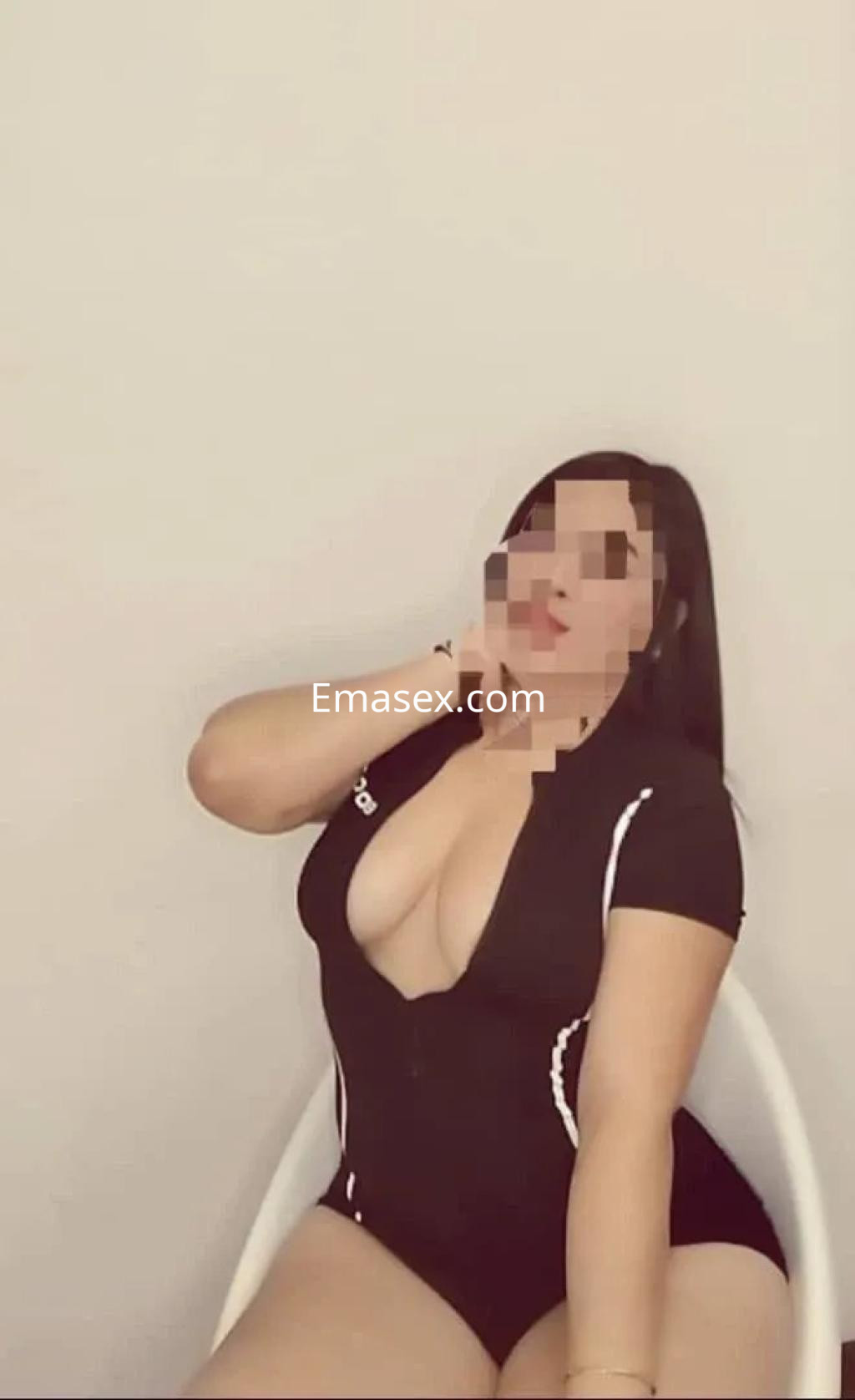 Escort en Burgos sentada en una silla, vistiendo un traje de baño negro que realza su figura.