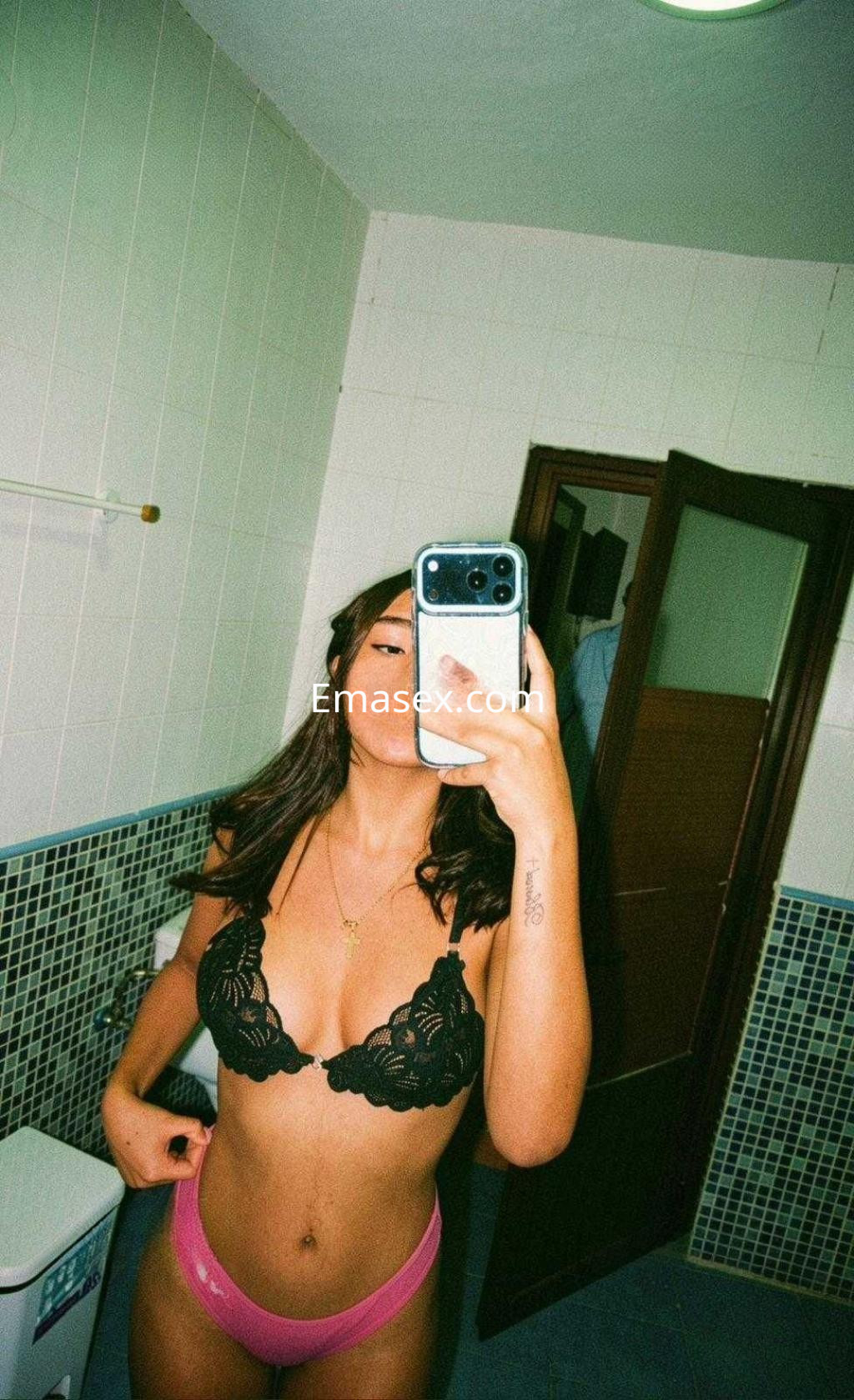 Puta en Córdoba se toma una selfie en el espejo, vistiendo un sujetador negro y braguitas rosas.