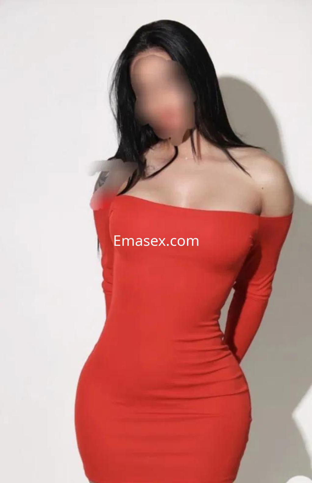 Puta de piel clara y cabello oscuro, viste un ajustado vestido rojo de manga larga en un fondo neutro en Madrid.