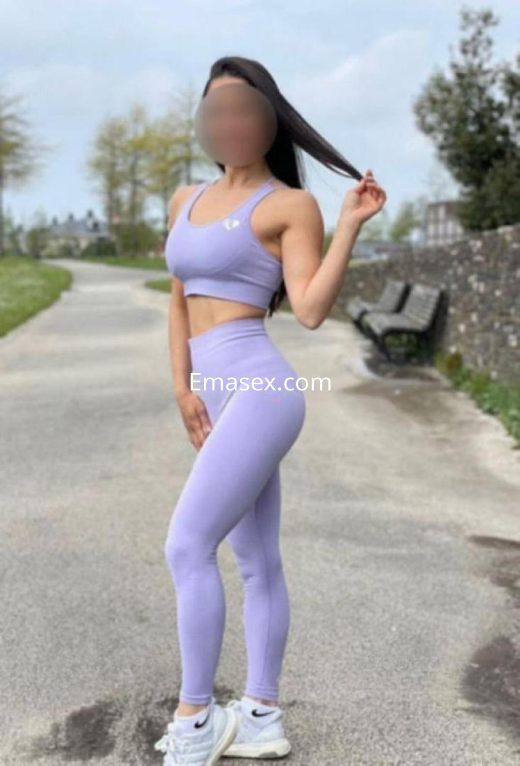 La escort viste un conjunto deportivo de color lila y zapatillas blancas, posando al aire libre en Madrid.