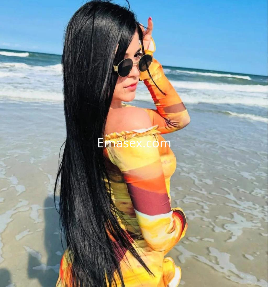 Puta con cabello largo y negro, vestida con un atuendo colorido, posando en la playa de Tarragona.