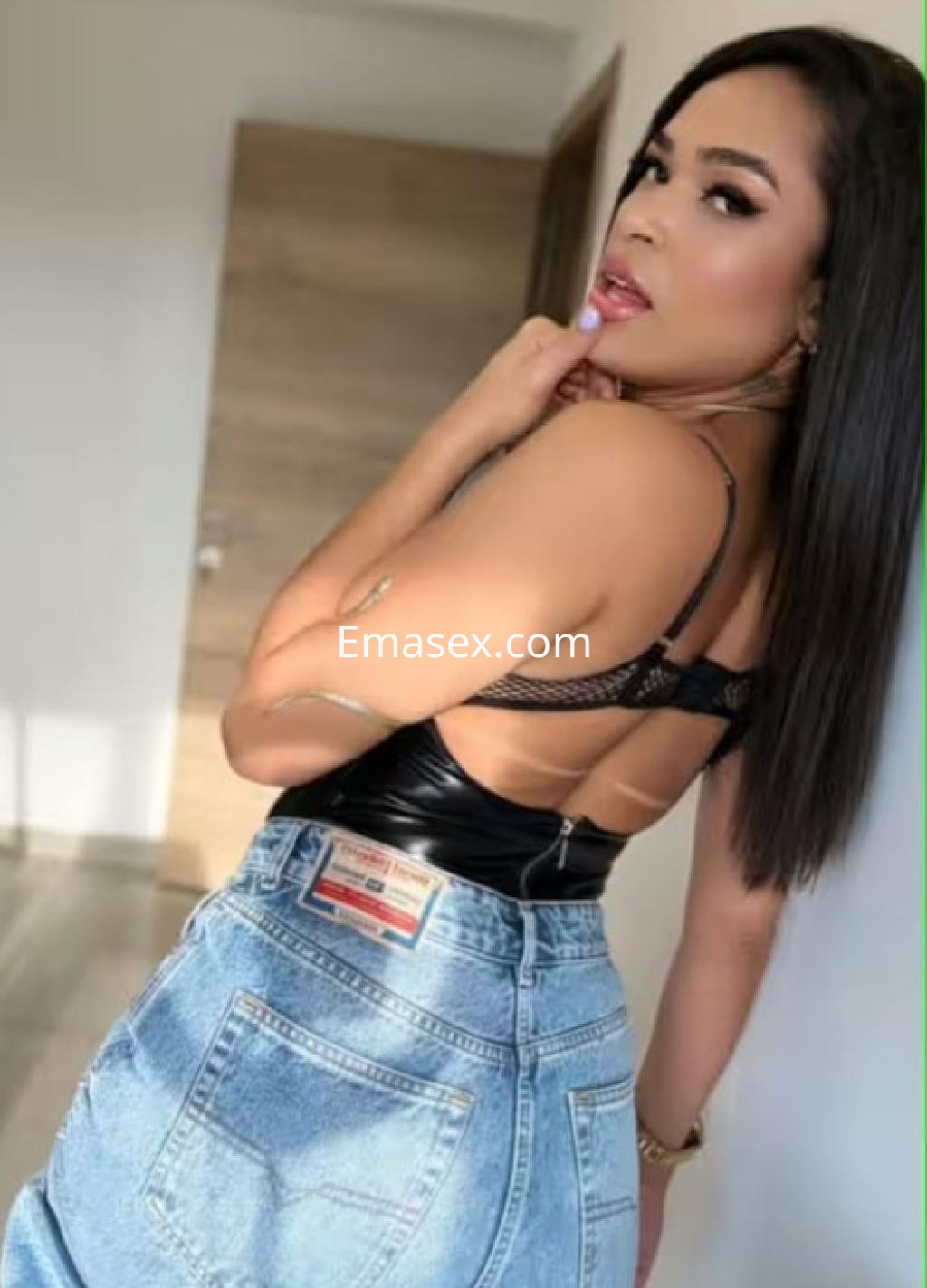 La puta muestra un atuendo de top negro y jeans cortos, posando de perfil en un entorno moderno en Pamplona.