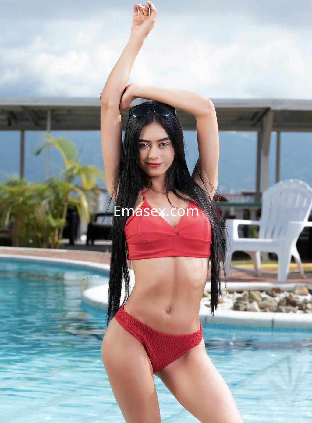 Escort en Donosti luciendo un bikini rojo, con cabello largo y lacio, posando junto a una piscina.