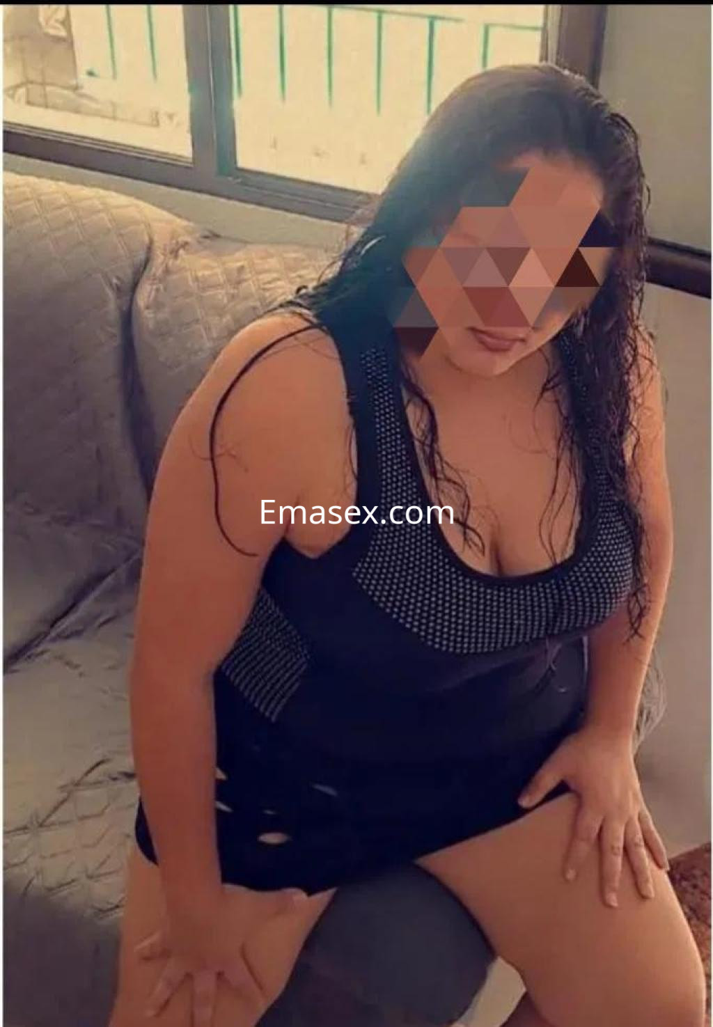 Puta sentada en un sofá, con vestido negro ajustado y detalles brillantes, en Badajoz.