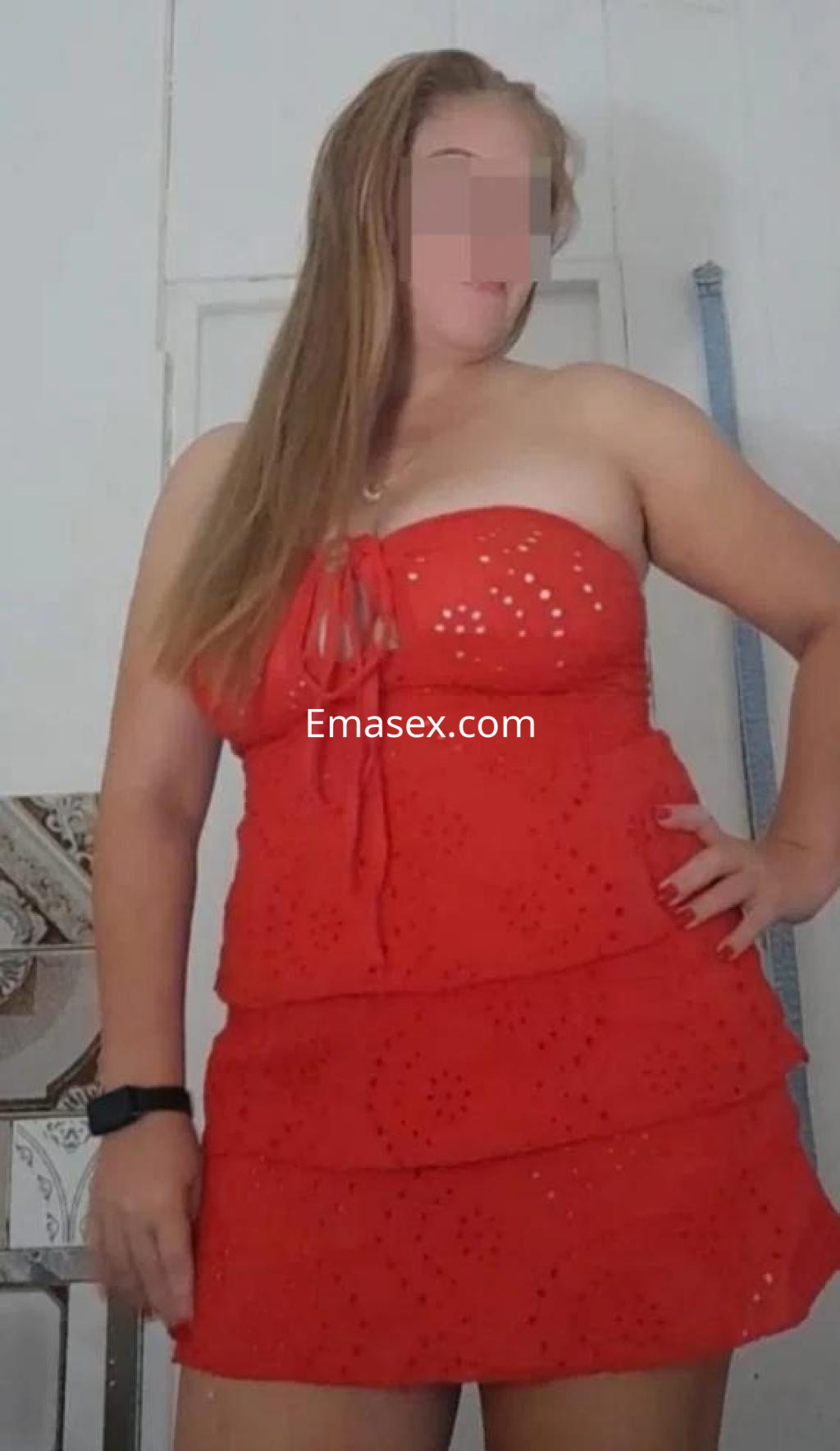La puta lleva un vestido rojo sin mangas, con detalles de bordado, posando en un entorno interior en Barcelona.