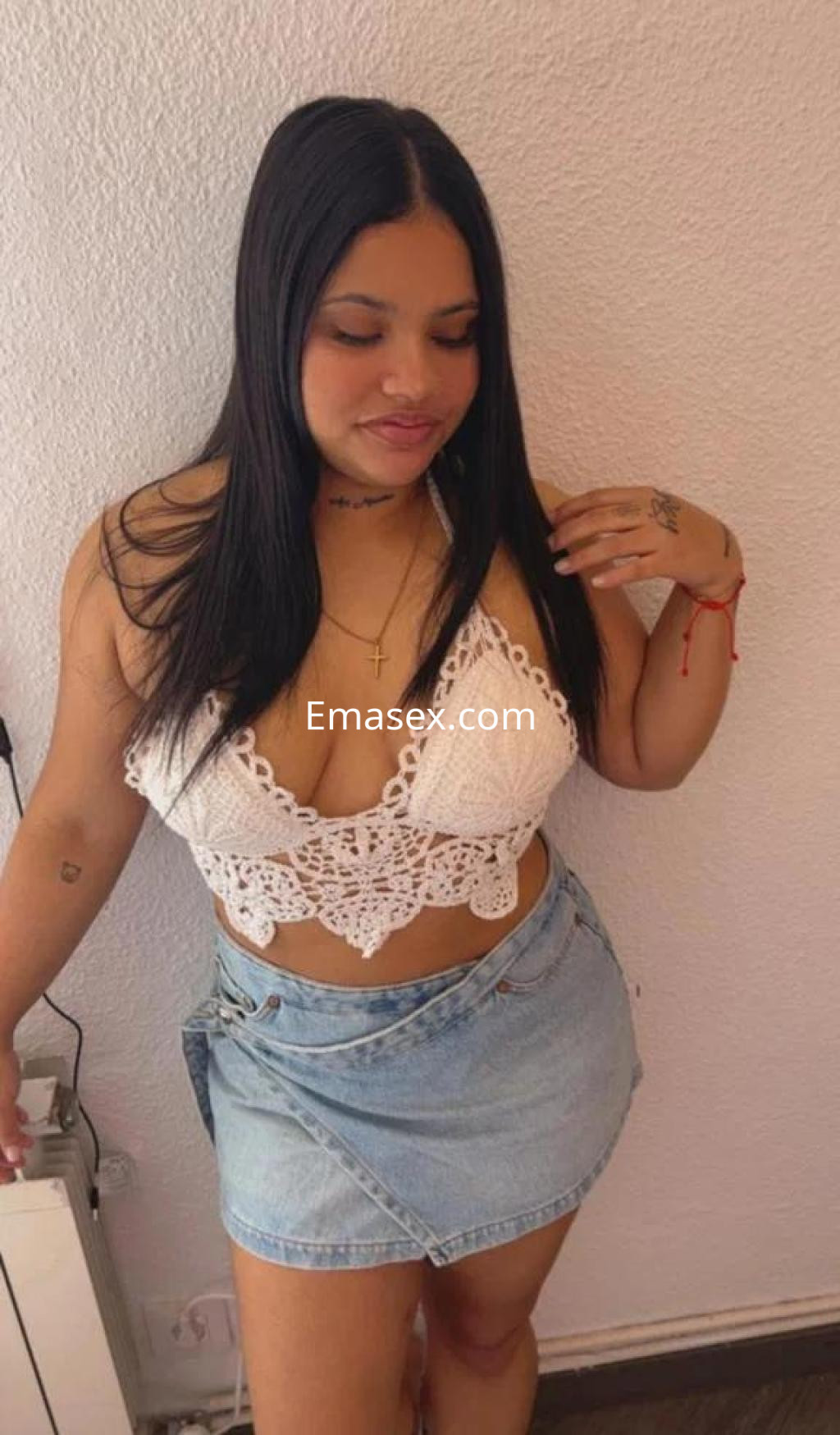 Puta en Madrid con cabello largo y lacio, viste un top de encaje blanco y una falda de mezclilla.