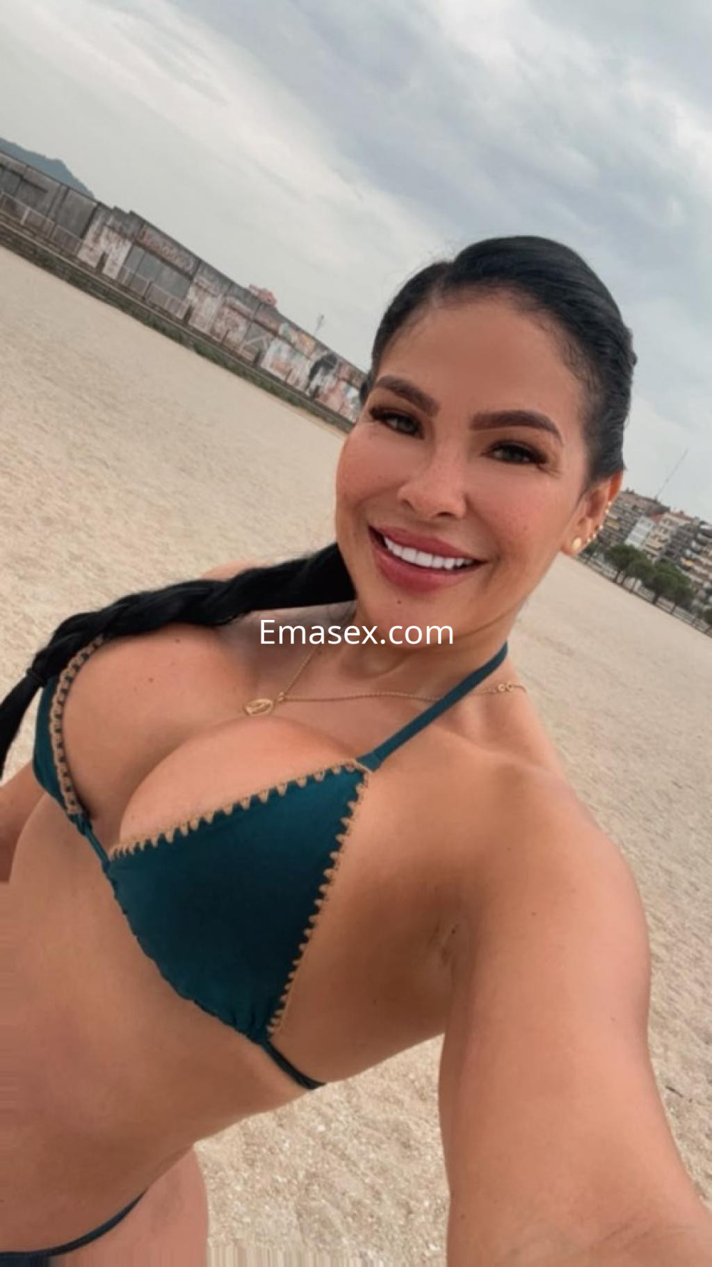 Puta sonriente en la playa de Pontevedra, luciendo un bikini verde y con el cabello trenzado.
