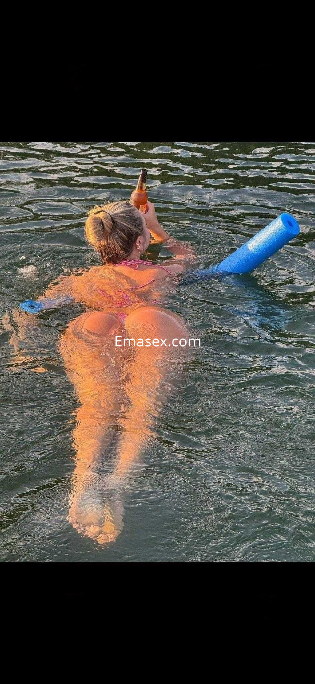 Puta en Tenerife, disfrutando de un día soleado en el agua con un bañador rosa y sosteniendo una botella.