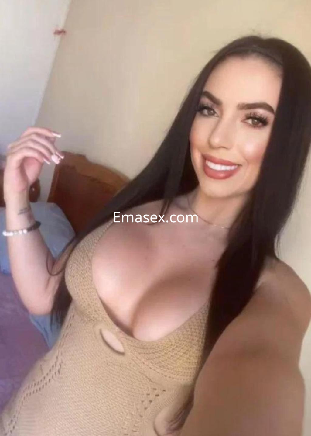 Puta en Almería, posando sonriente con un vestido ajustado de color beige que resalta su figura.