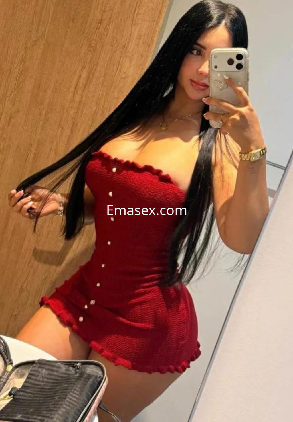 Escort en Almería con vestido ajustado rojo y largo cabello lacio, posando en un espejo.