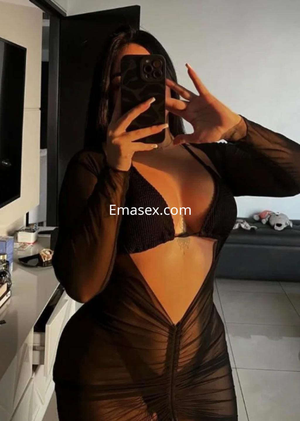 La escort en Pamplona se muestra con un vestido negro transparente que resalta su figura, mientras toma una selfie.