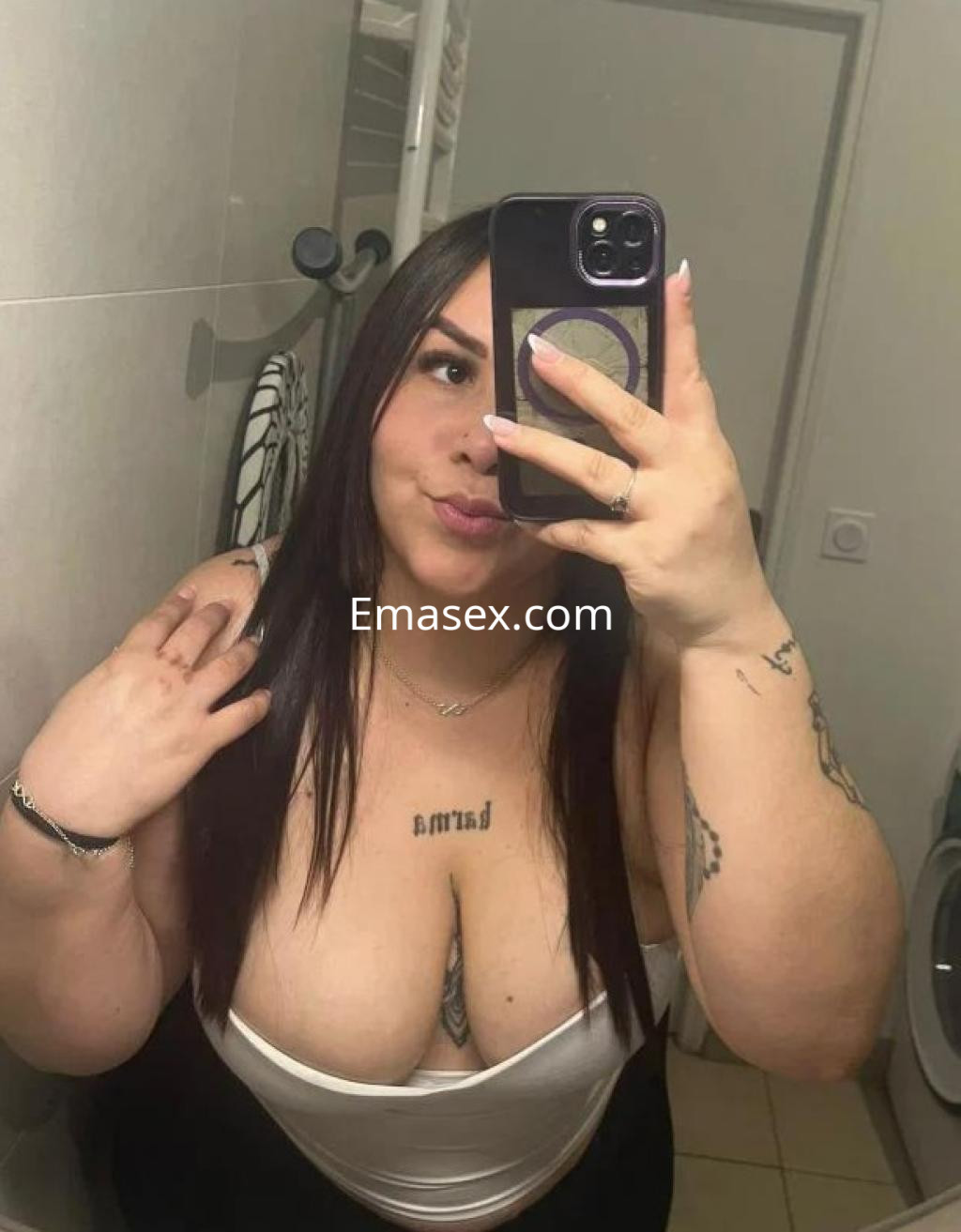 Escort en Madrid con cabello largo y lacio, luciendo un top blanco en un baño, posando para la cámara.