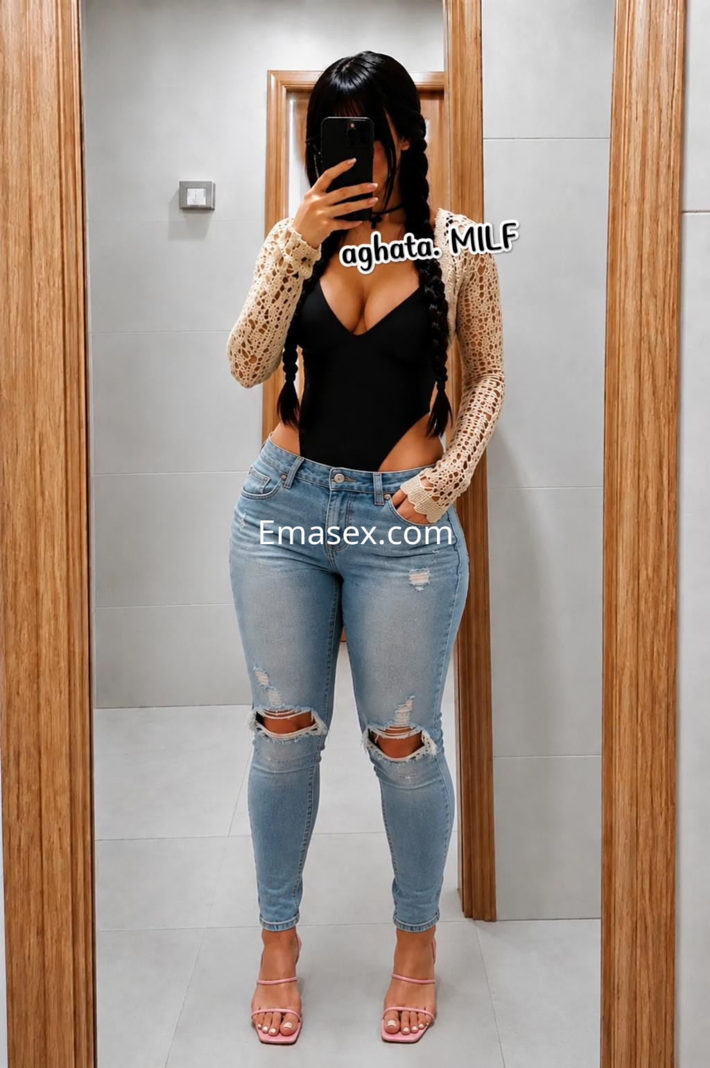 Escort en Logroño con cabello largo y trenzado, viste un body negro y jeans ajustados con roturas.