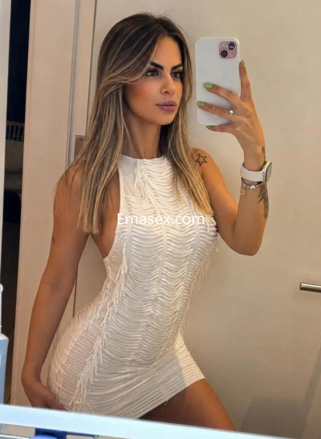 La escort en Las Palmas se toma una selfie luciendo un vestido blanco ajustado con detalles de franja.