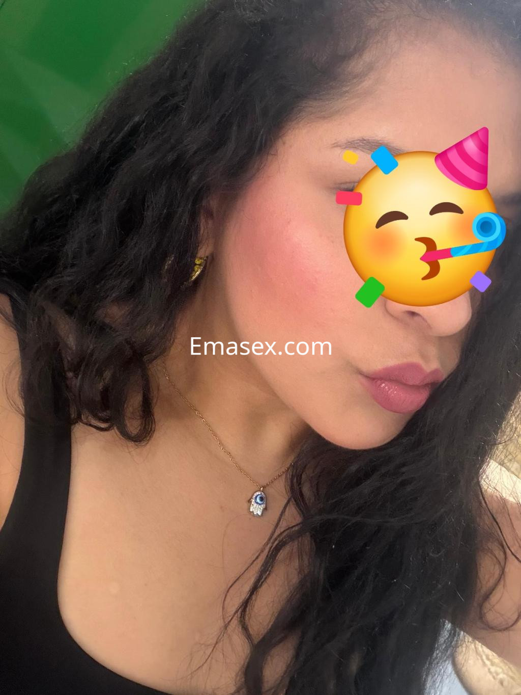 Escort en Valladolid con cabello rizado y suelto, luciendo un top negro y un collar sencillo.