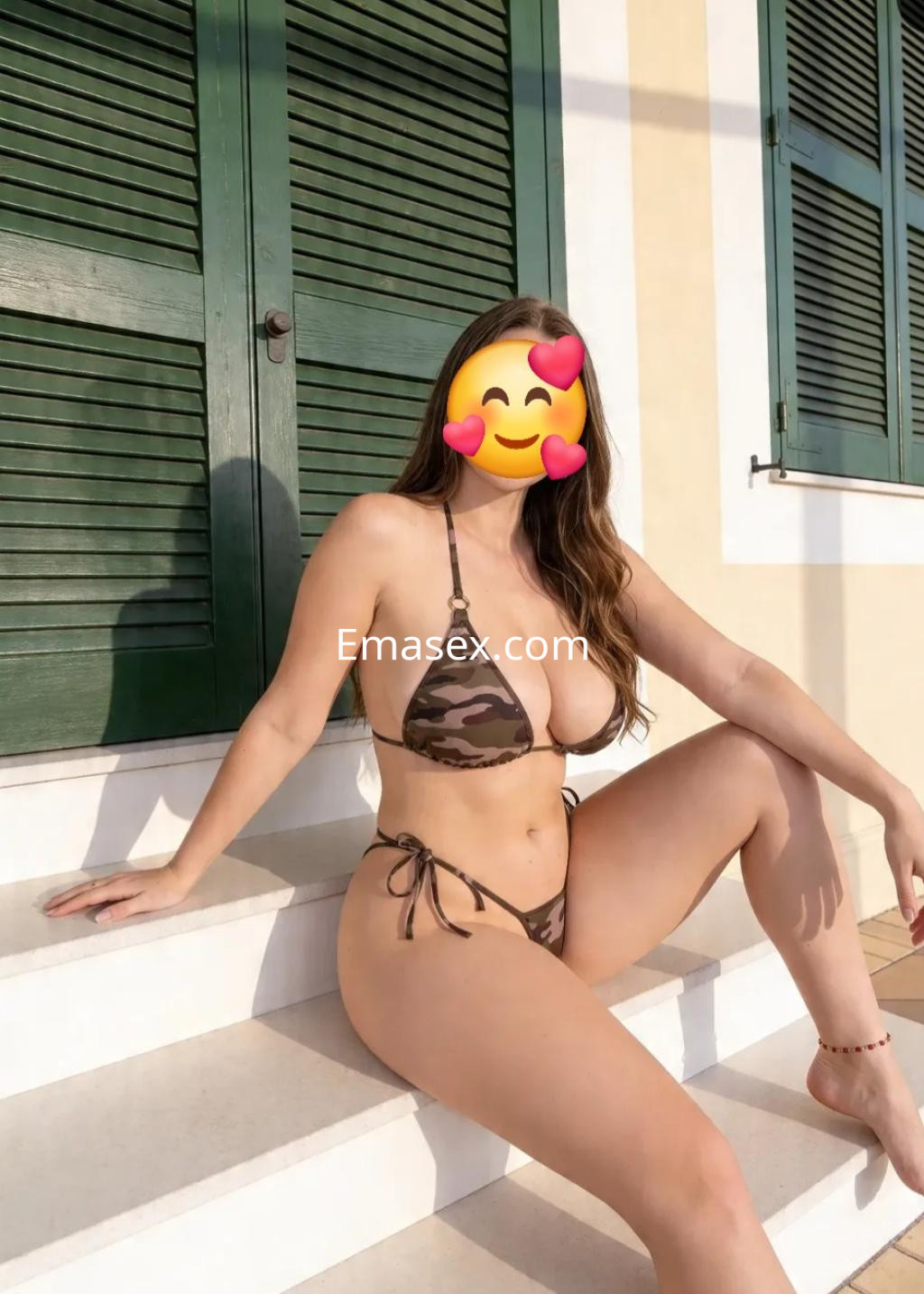 Puta posando en Logroño con un bikini de camuflaje, sentada en unas escaleras, con fondo de persianas verdes.