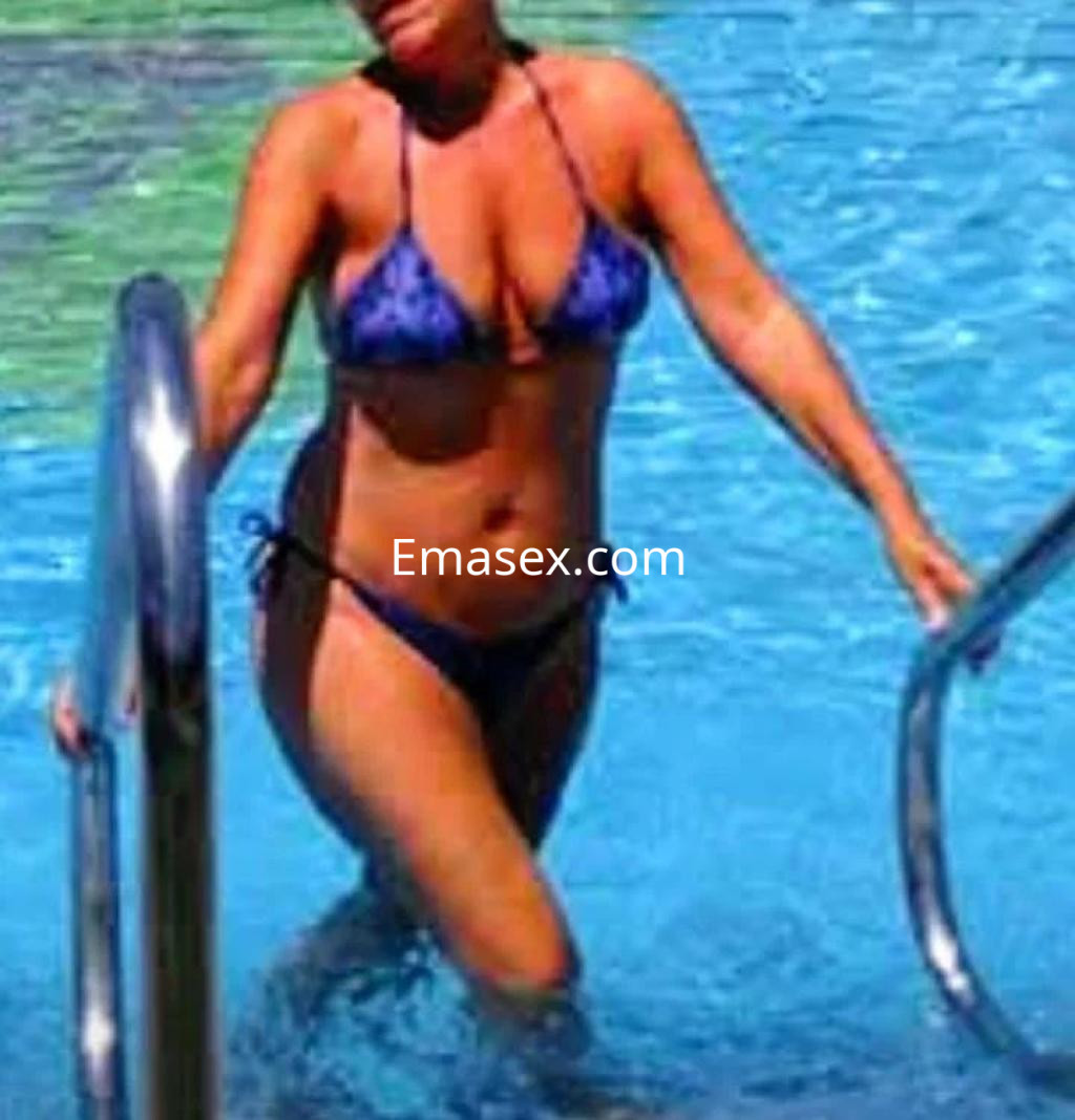 Puta en Alicante, luciendo un bikini azul mientras sale de una piscina, con el cabello suelto y húmedo.