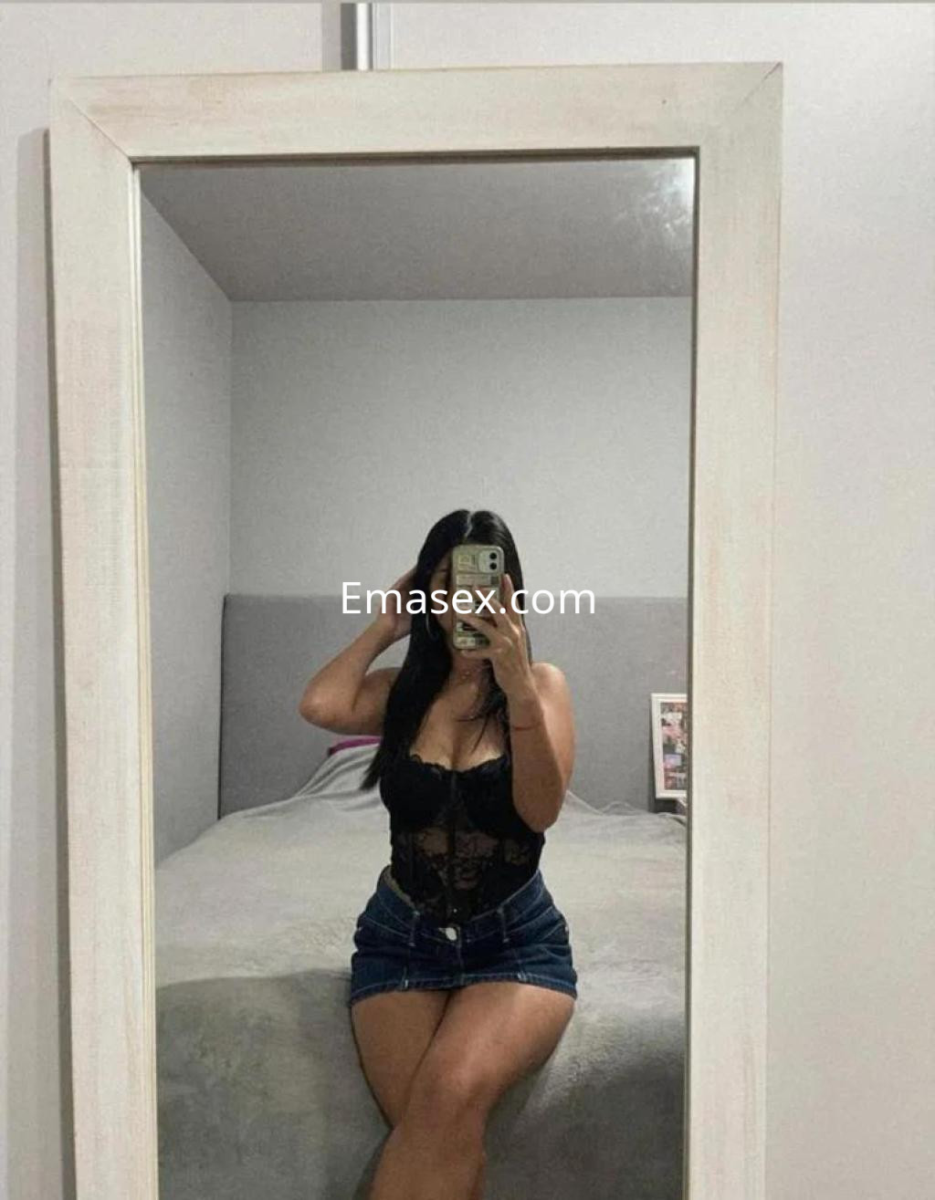 Puta posando frente al espejo con un corsé negro y una falda de mezclilla en un ambiente interior en Burgos.