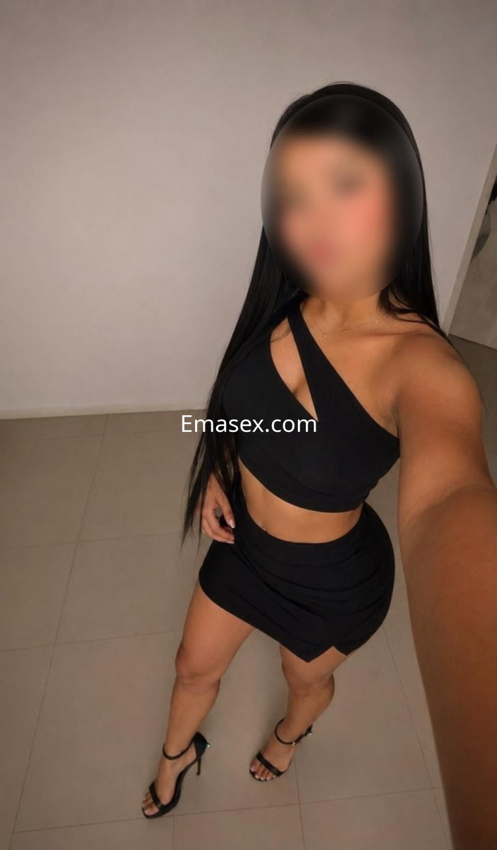 Escort en Lleida, con cabello largo y lacio, viste un conjunto negro con detalles cut-out y tacones altos.