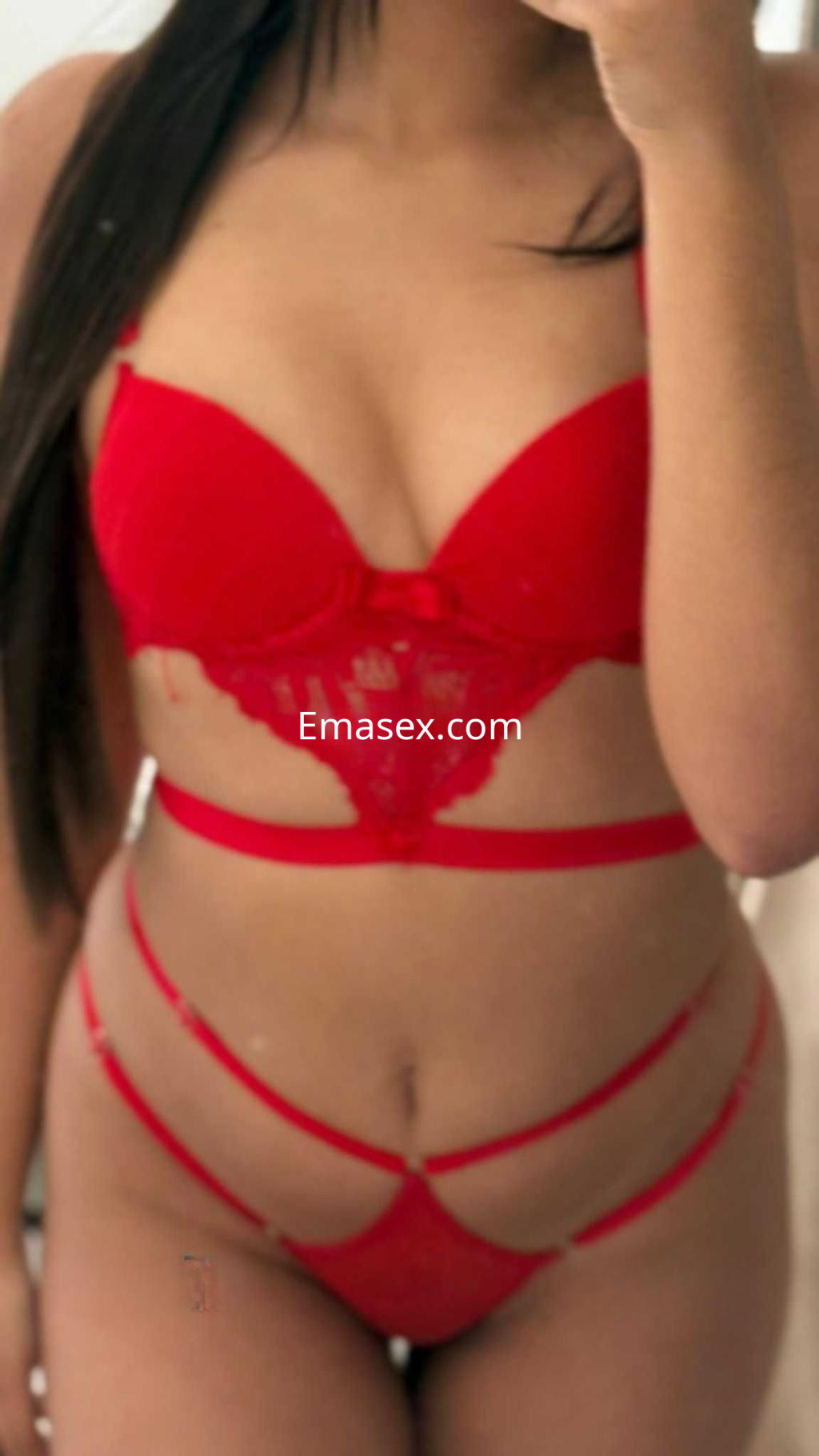 Escort en Madrid luciendo un conjunto de lencería roja con detalles de encaje y tiras, en un espejo.