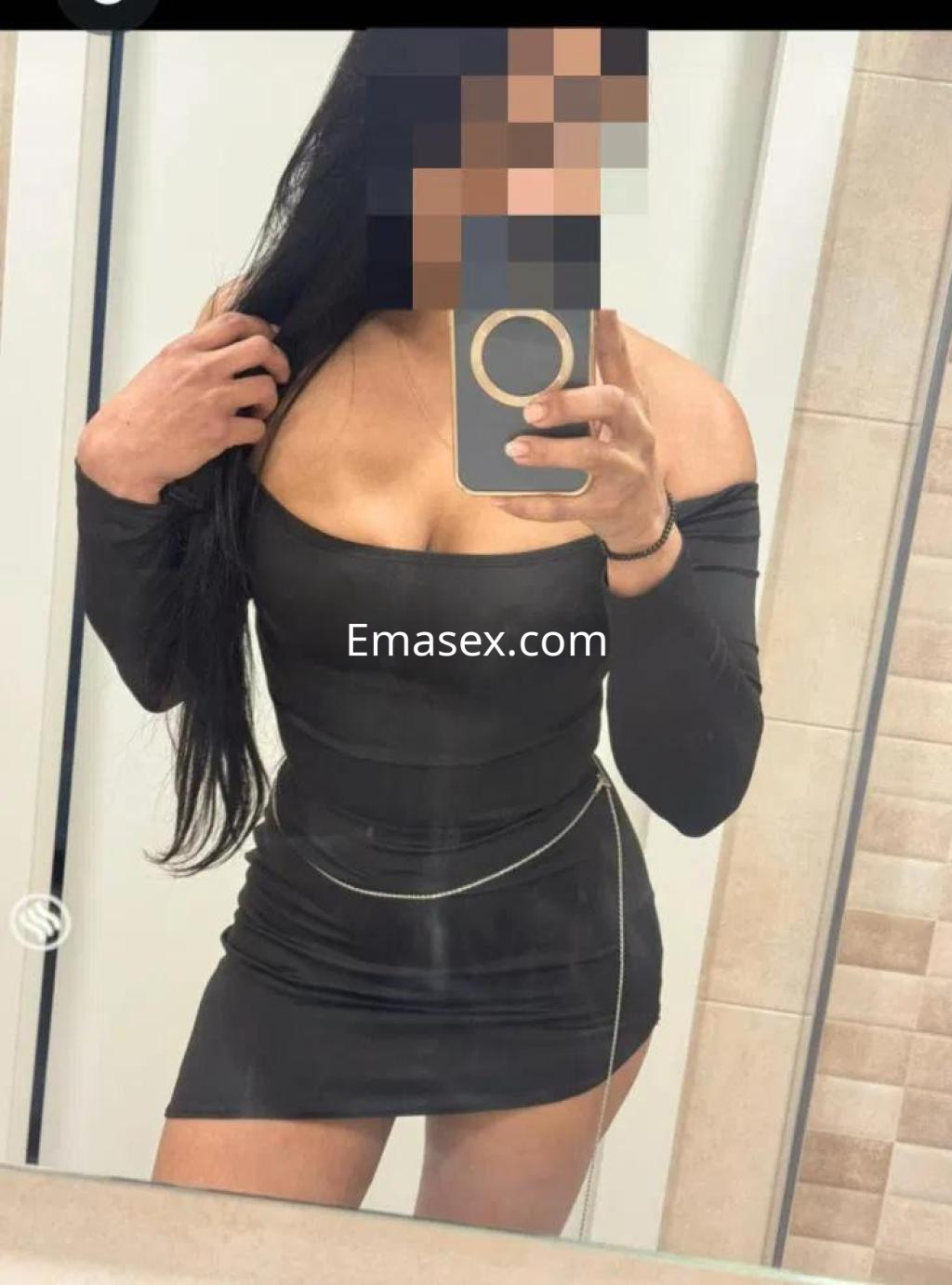 Escort en Tarragona posando frente al espejo con vestido negro ajustado y cabello largo, luciendo elegante.