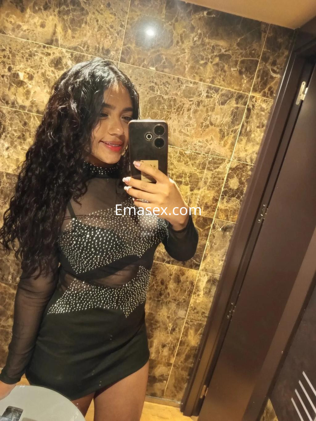 La puta en Valladolid se muestra en un vestido negro ajustado con detalles brillantes y cabello rizado.