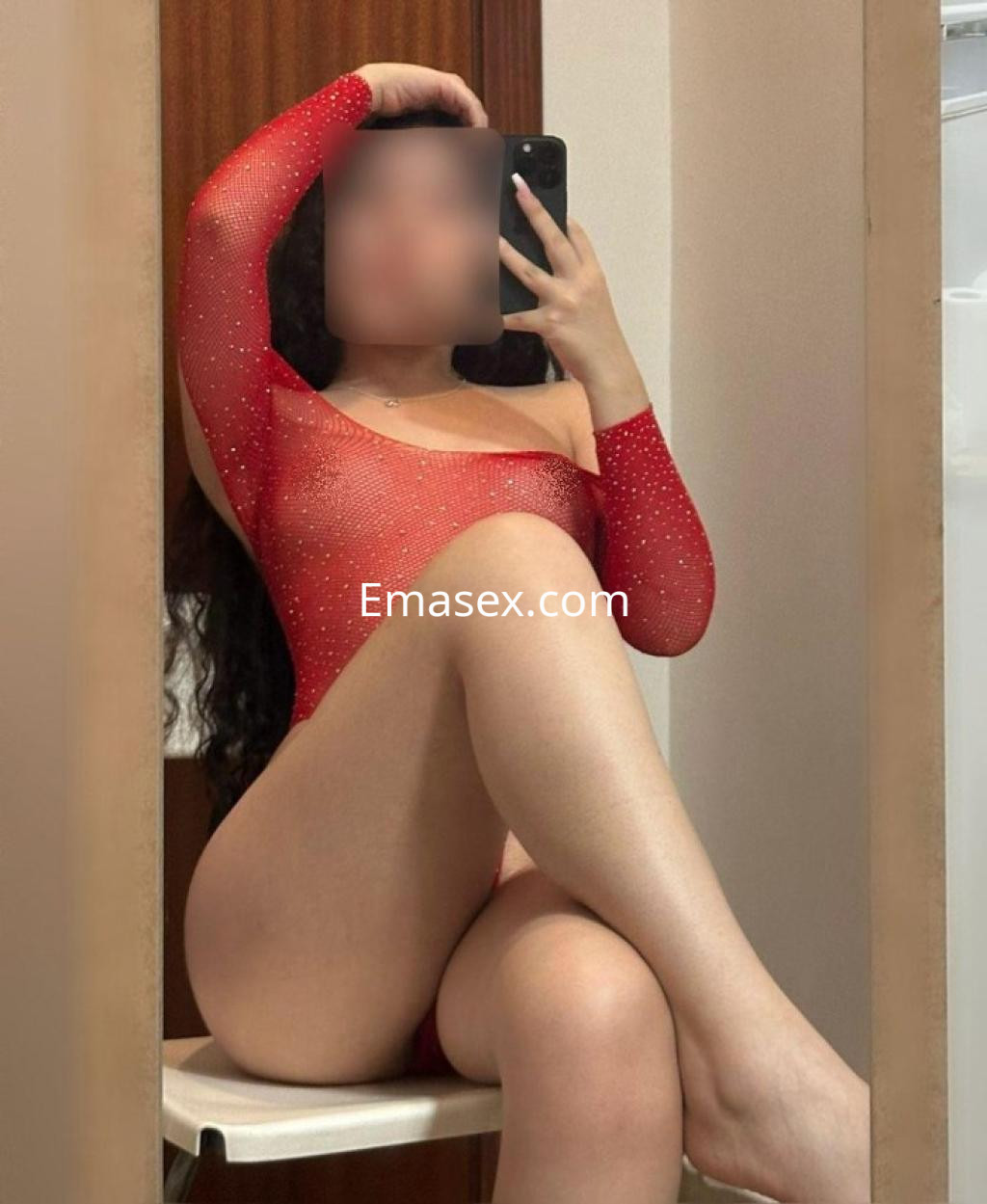 La puta se muestra en un body rojo con detalles brillantes, posando en un espejo en Almería.