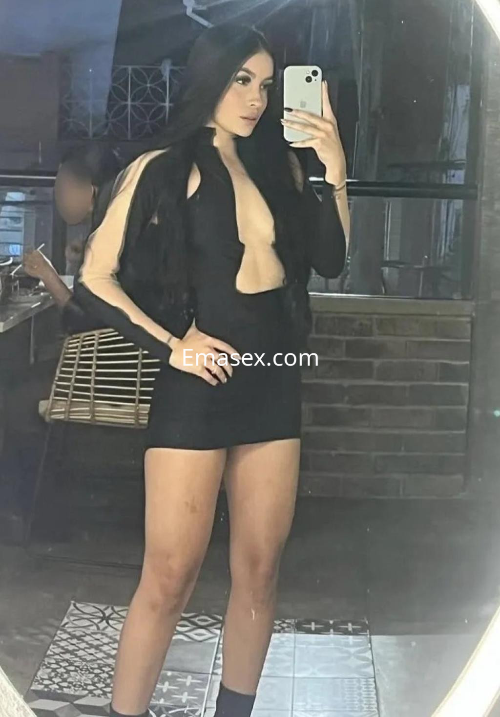 La puta luce un vestido negro con escote pronunciado y refleja su imagen en un espejo en Málaga.