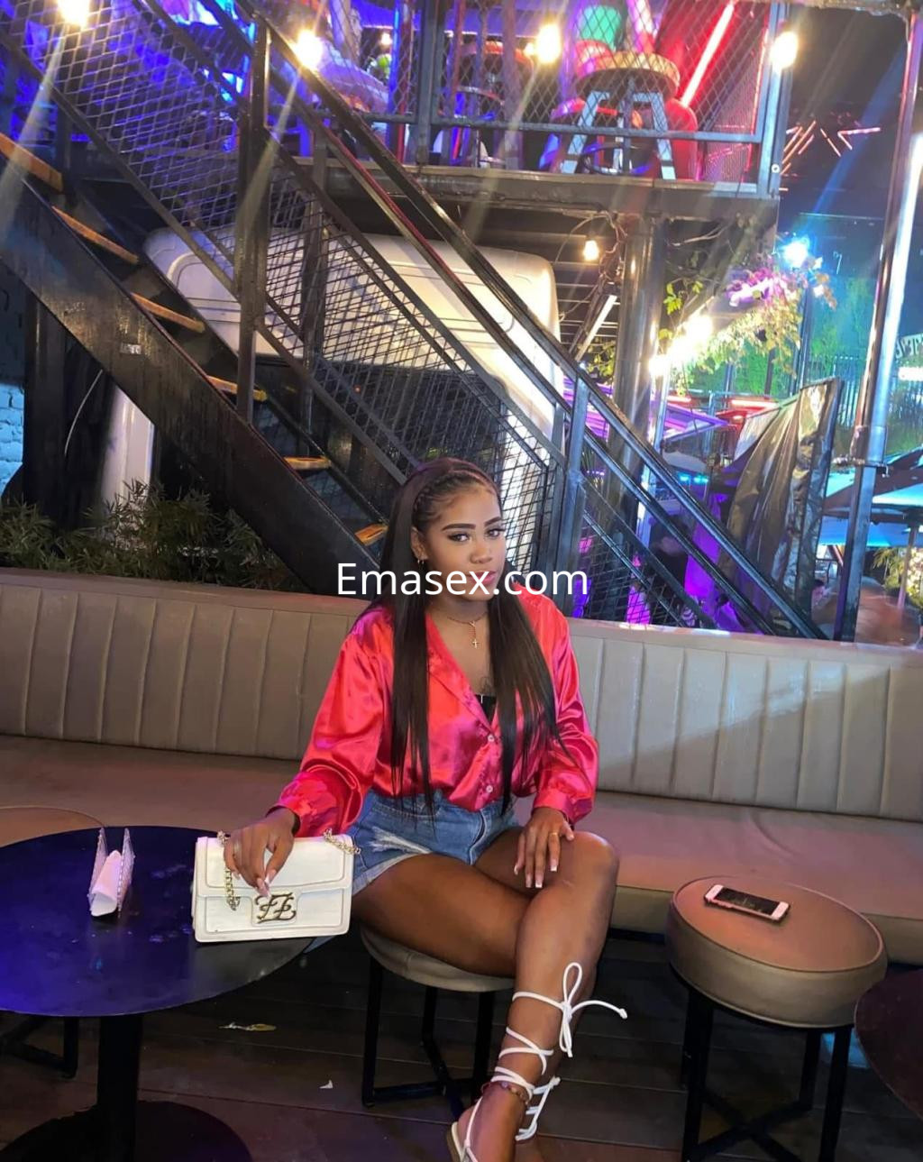 Puta con blusa de satén rosa y shorts de mezclilla sentada en un bar de Bilbao, con un ambiente iluminado.