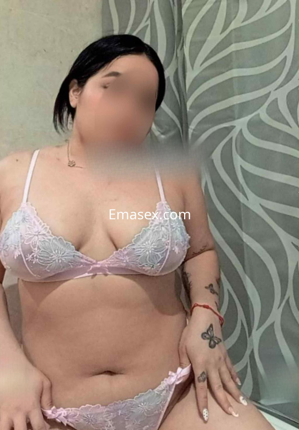 Puta en Barcelona, posando con lencería rosa con detalles de encaje, mostrando su tatuaje en una mano.