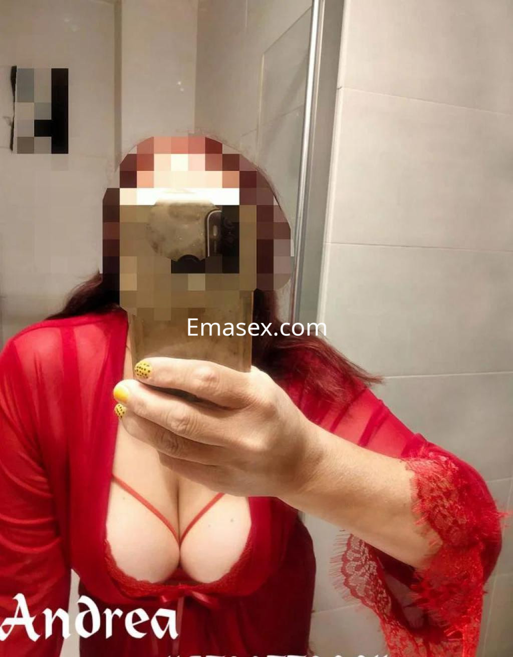 Puta de cabello largo y rojo, luciendo una bata roja semi-transparente mientras se toma una selfie en un baño en Granada.