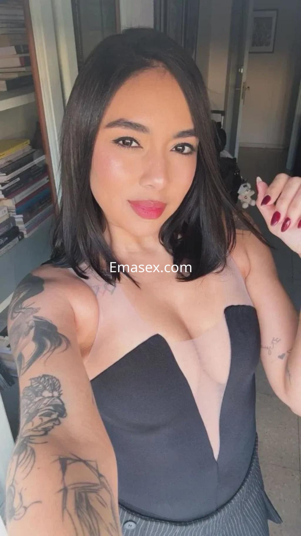 La escort en Málaga posa con un top negro de escote pronunciado y un maquillaje natural, mostrando sus tatuajes.