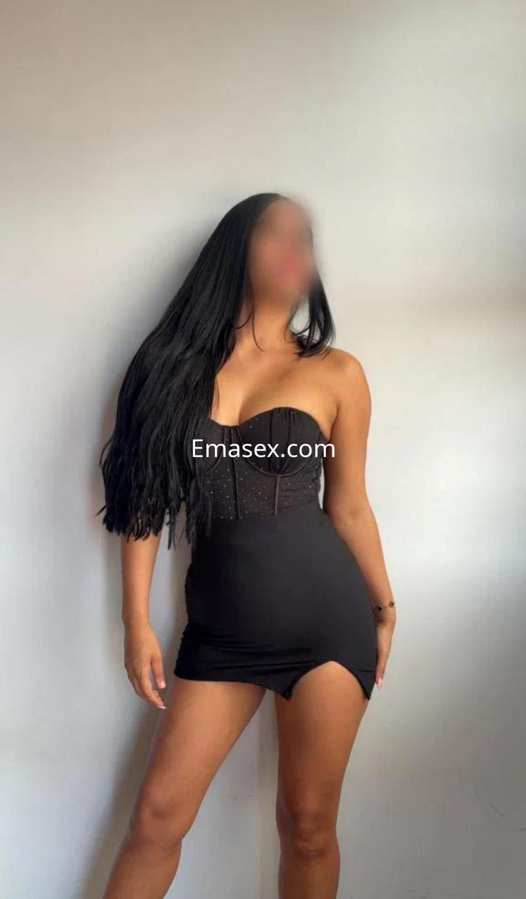 Escort en Murcia con vestido negro ajustado y tirantes, cabello largo y lacio que cae sobre los hombros.