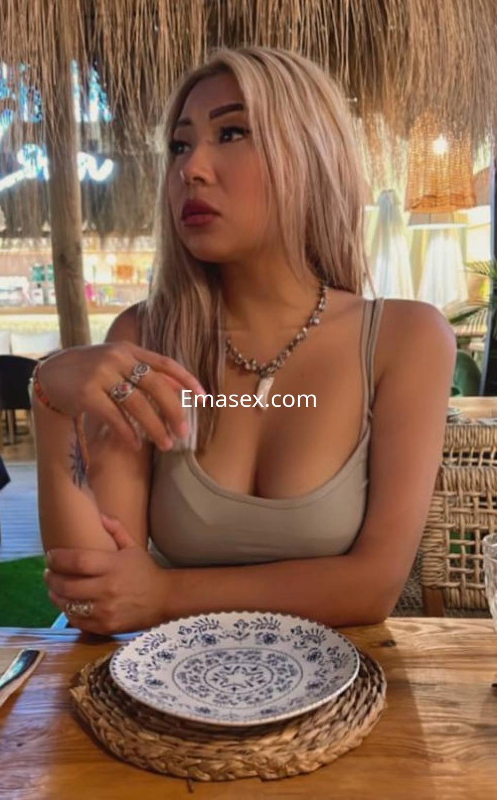 Puta con cabello rubio y lacio, viste una blusa sin mangas y posa pensativa en un ambiente acogedor de Santander.