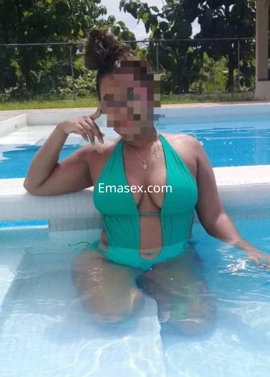 Puta en Córdoba, posando en una piscina con un traje de baño verde y el cabello recogido, sonriendo.